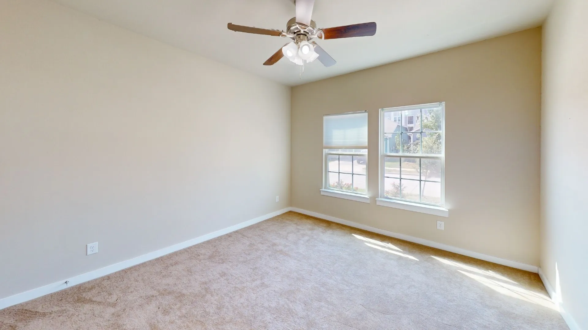 Vaulted ceiling featuring a ceiling fan with light fixture, two windows with blinds, and carpeted flooring