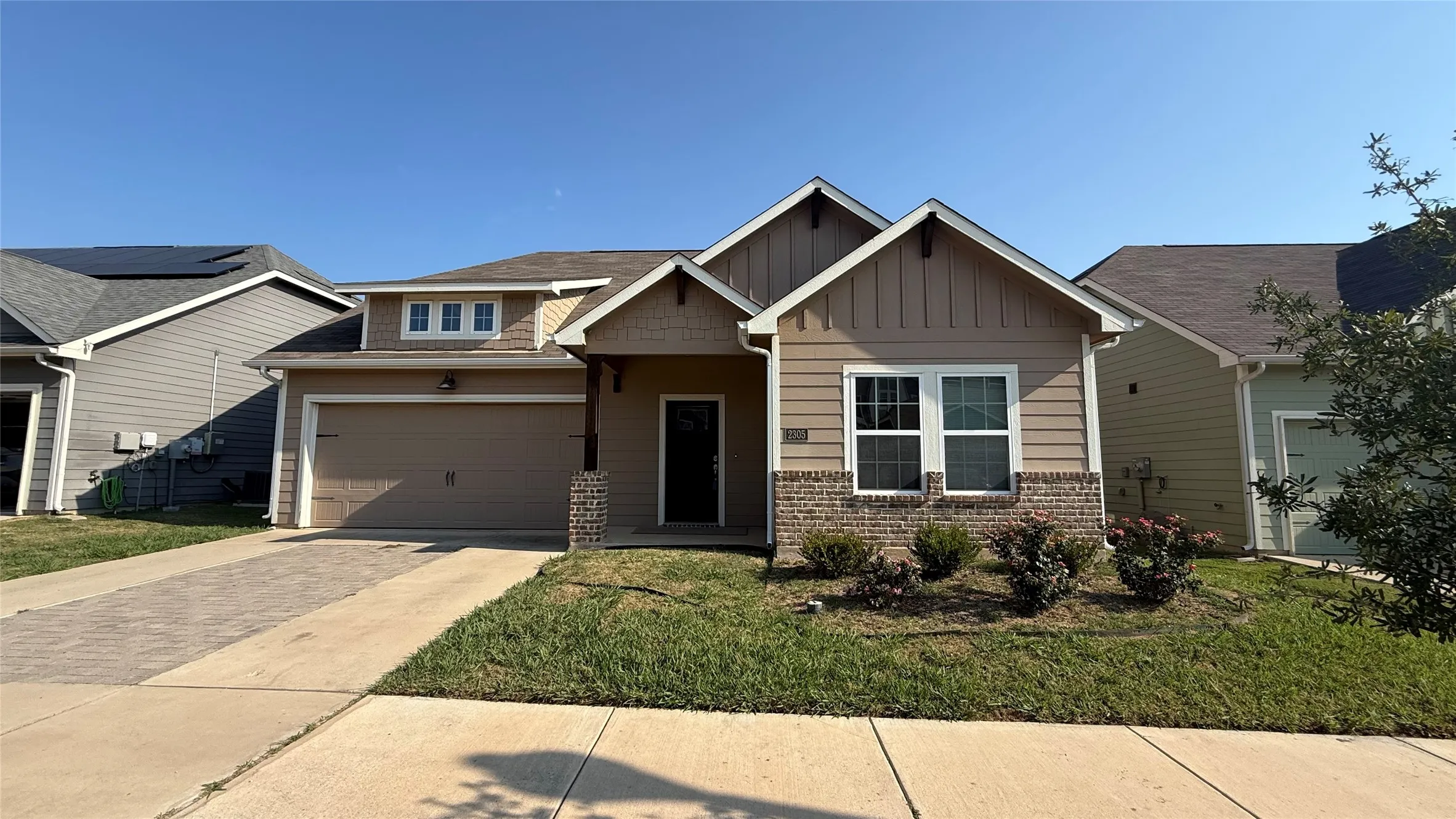 Single-story residence featuring a two-car garage, brick and siding exterior, and a paved driveway