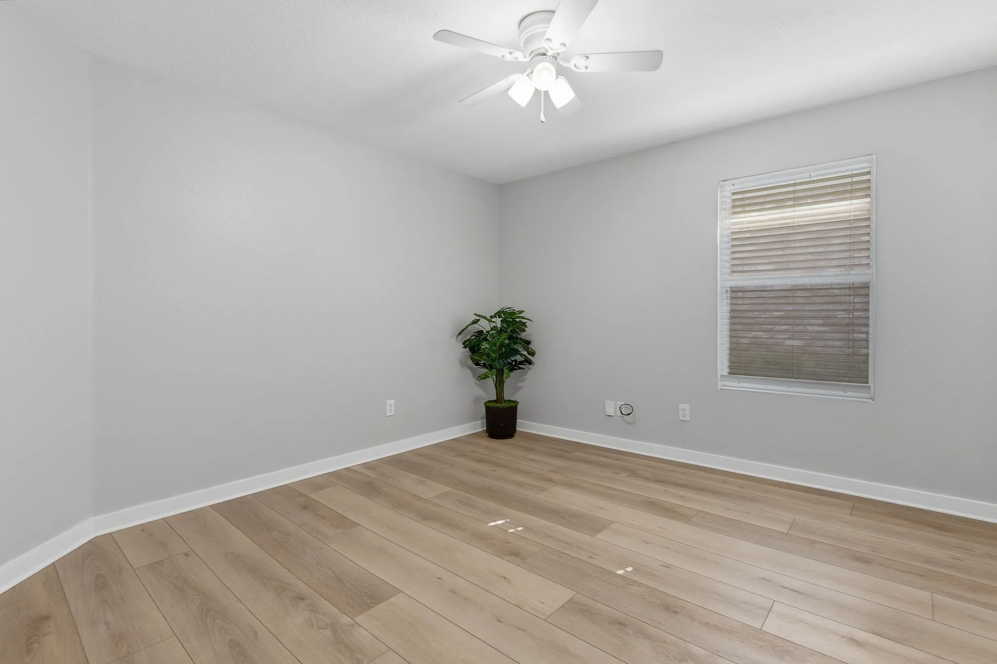 Bright secondary bedroom offers LVP flooring, a ceiling fan, natural light and a neutral move-in-ready palette.