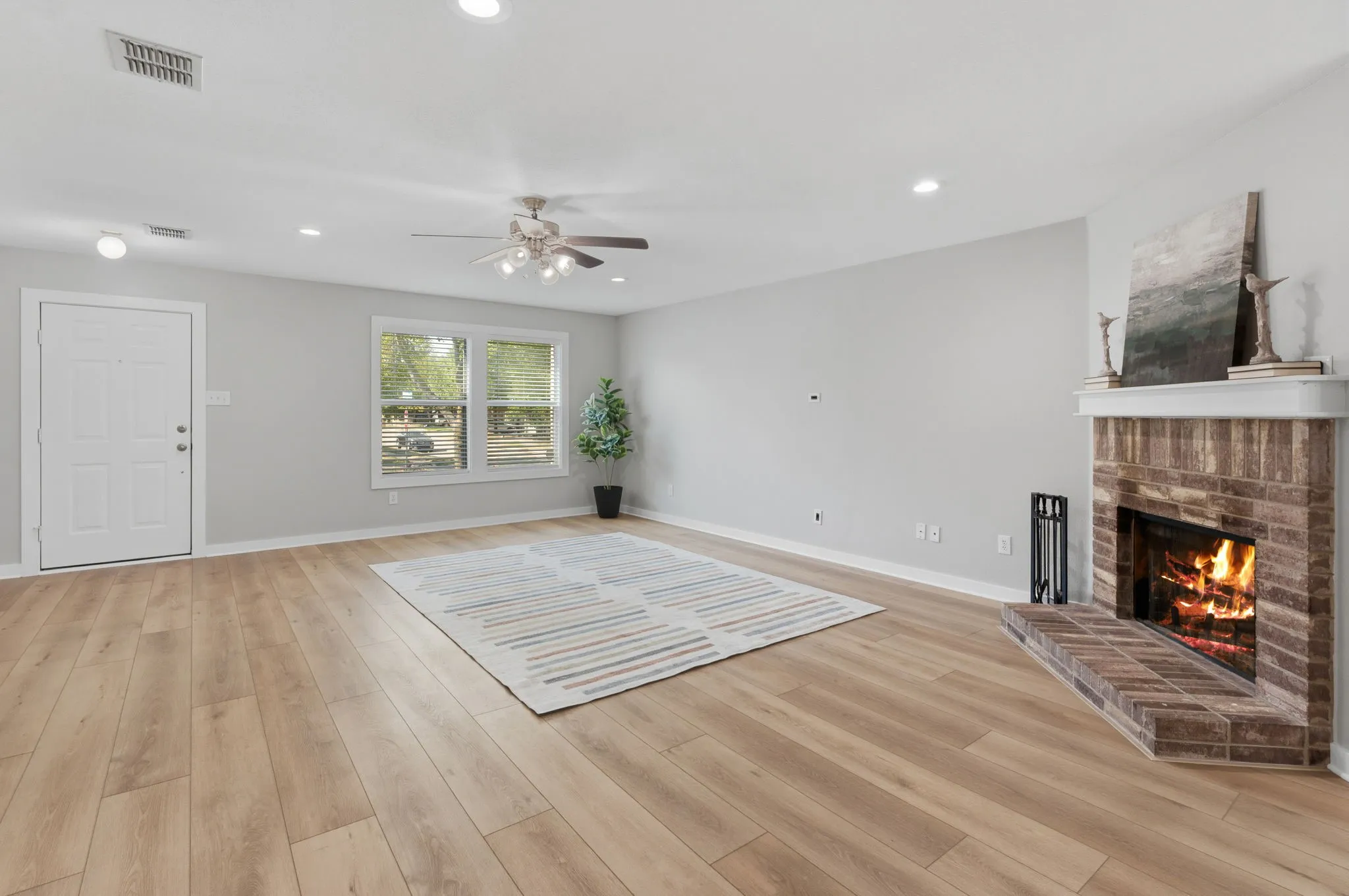 Spacious family room features updated LVP flooring, recessed lighting and a classic brick wood-burning fireplace.