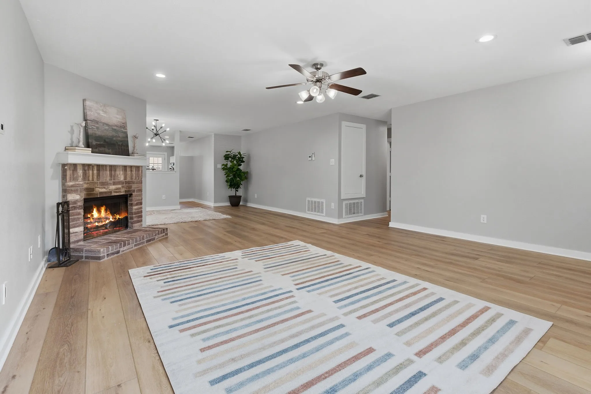 Spacious family room features updated LVP flooring, recessed lighting and a classic brick wood-burning fireplace.