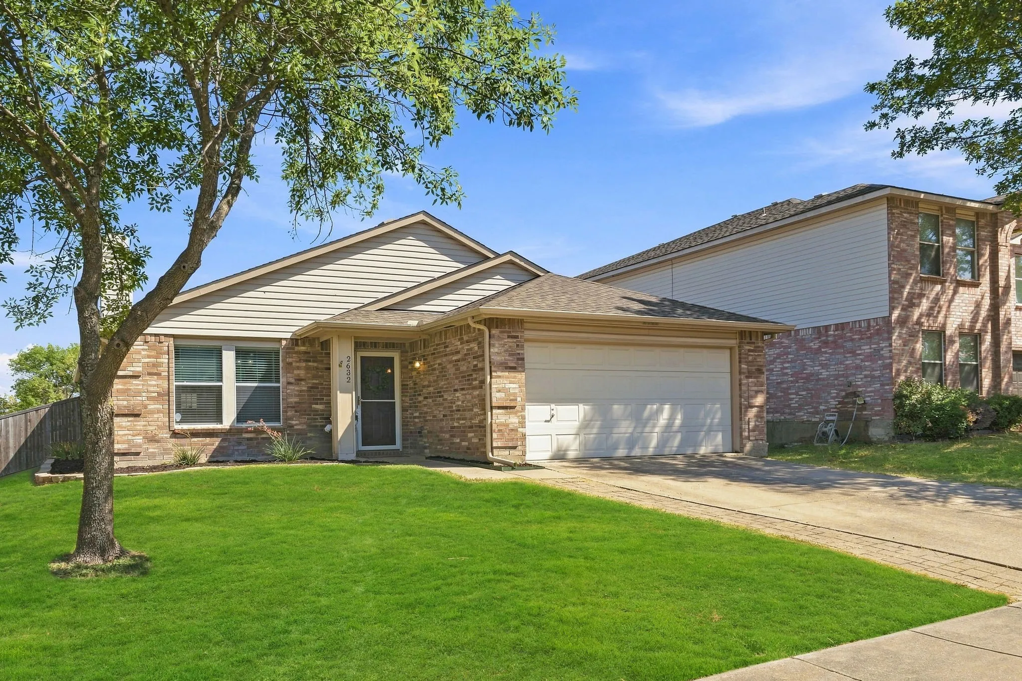 Welcoming front exterior highlights the home’s brick accents, two-car garage, mature tree and attractive corner-lot setting.