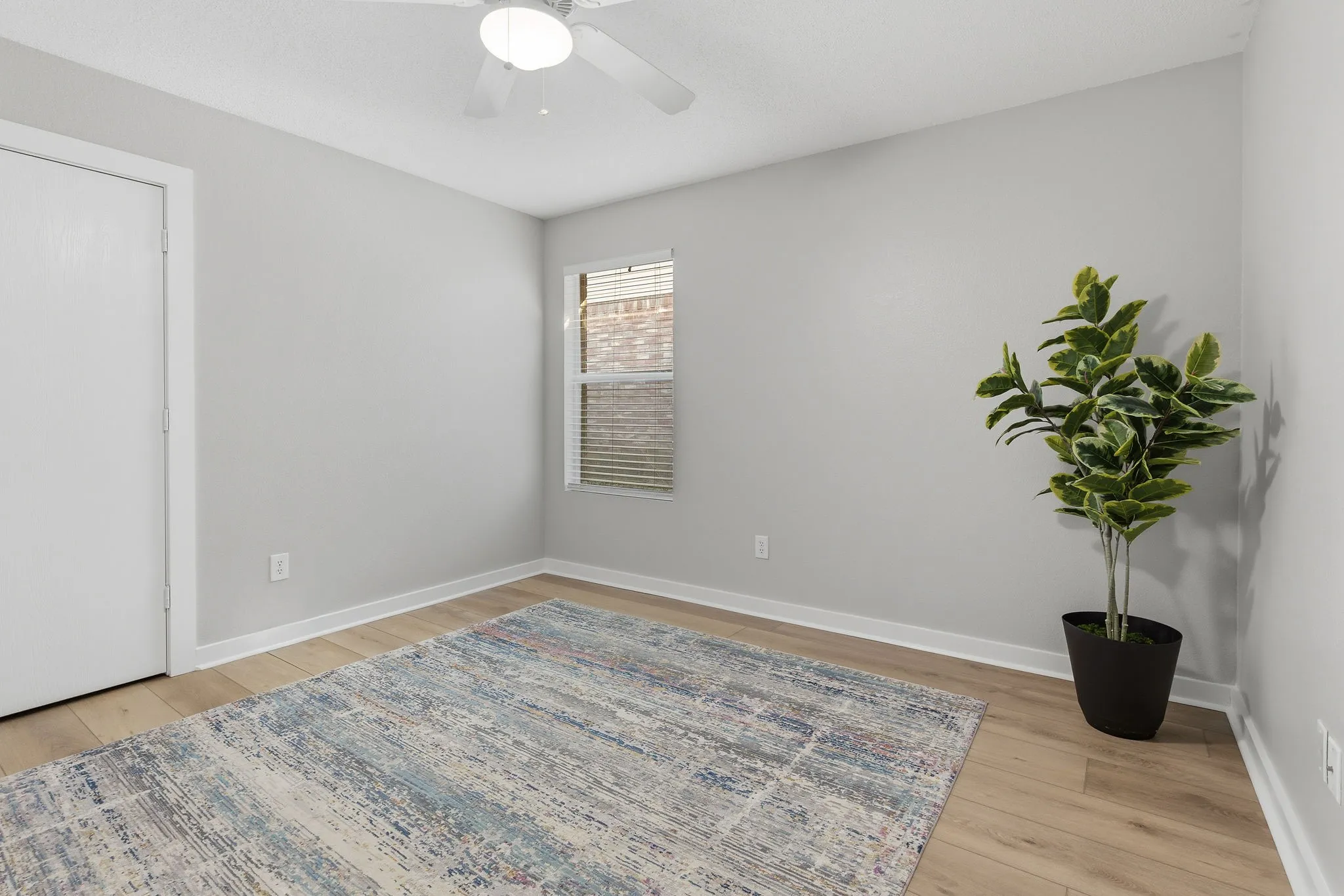 Comfortable secondary bedroom features LVP flooring, neutral finishes, a ceiling fan and ample wall space for furniture.