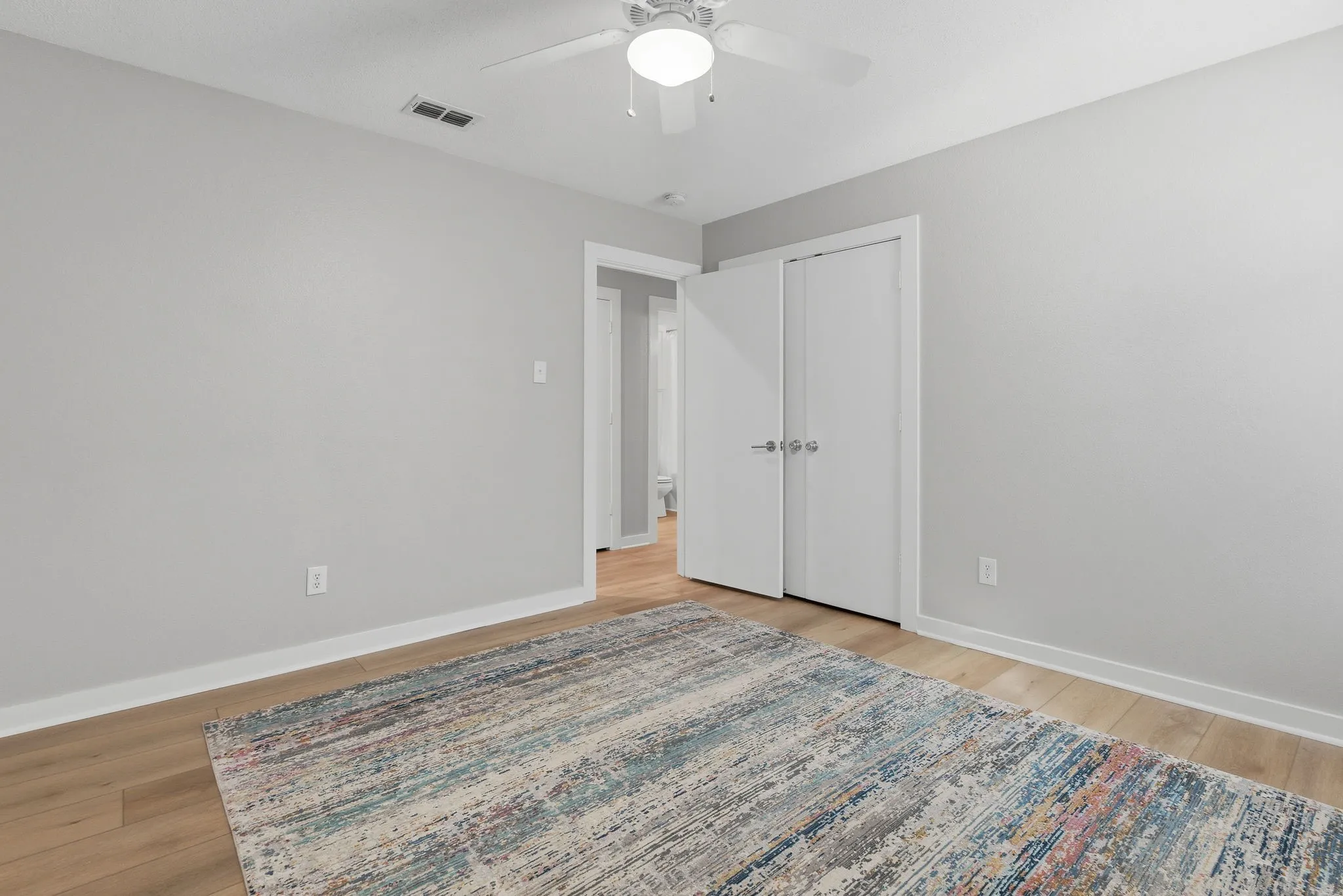 Comfortable secondary bedroom features LVP flooring, neutral finishes, a ceiling fan and ample wall space for furniture.