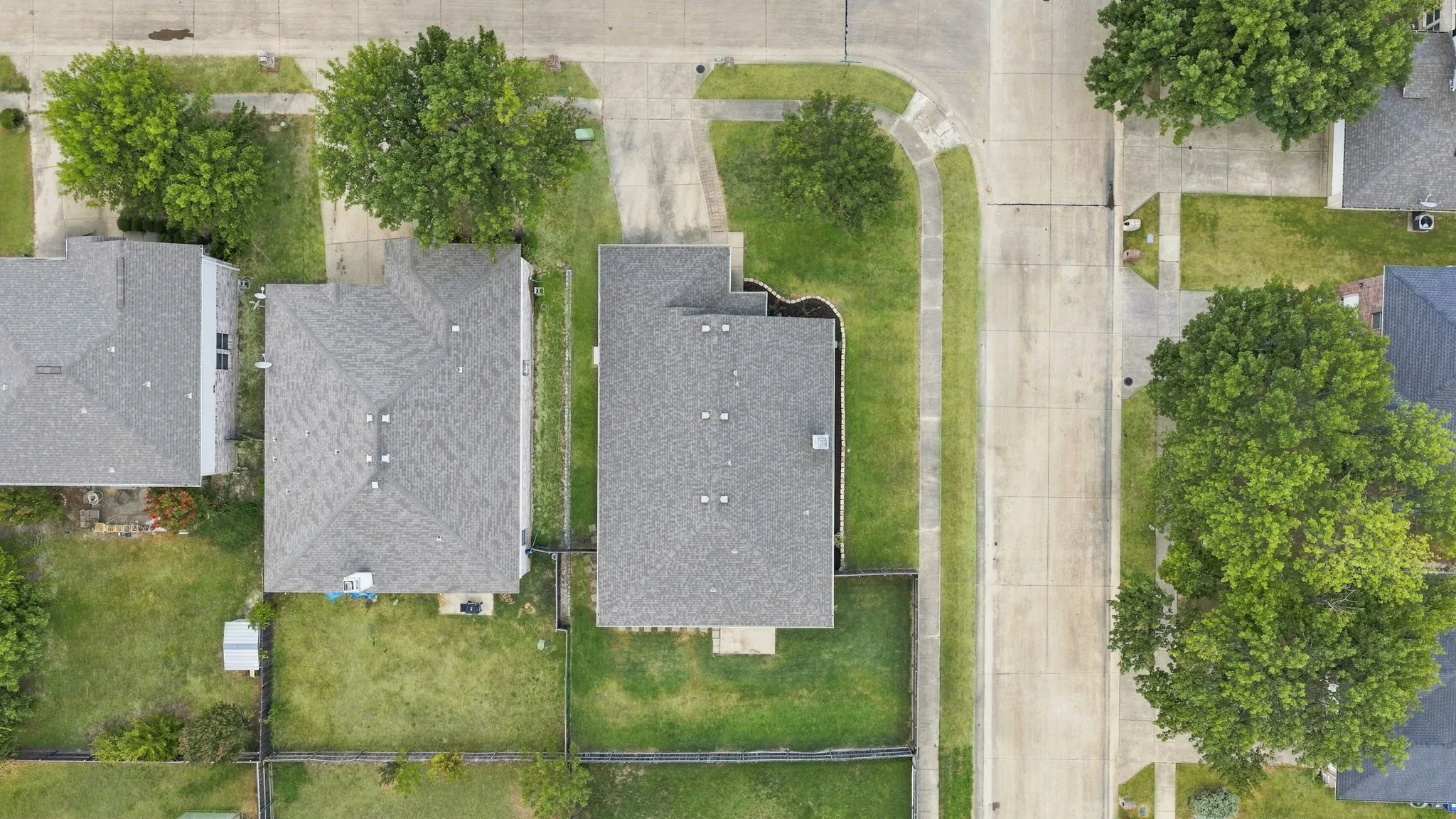 Overhead aerial view showcases the home’s corner-lot setting, fenced backyard and surrounding neighborhood.