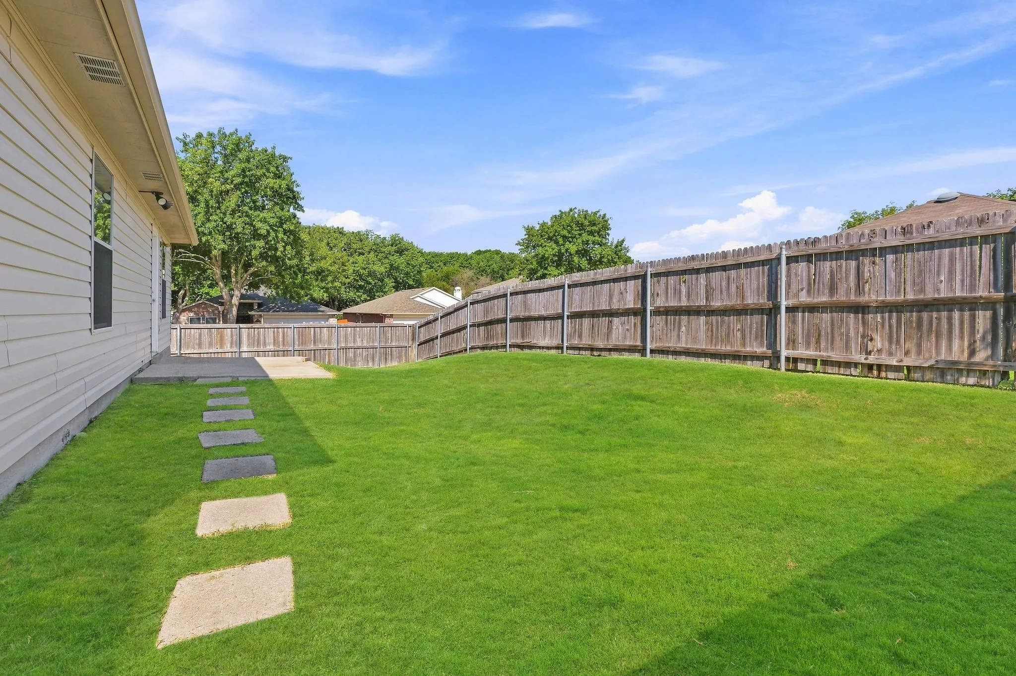 Another backyard view highlights the usable lawn, privacy fencing and convenient access from the home.