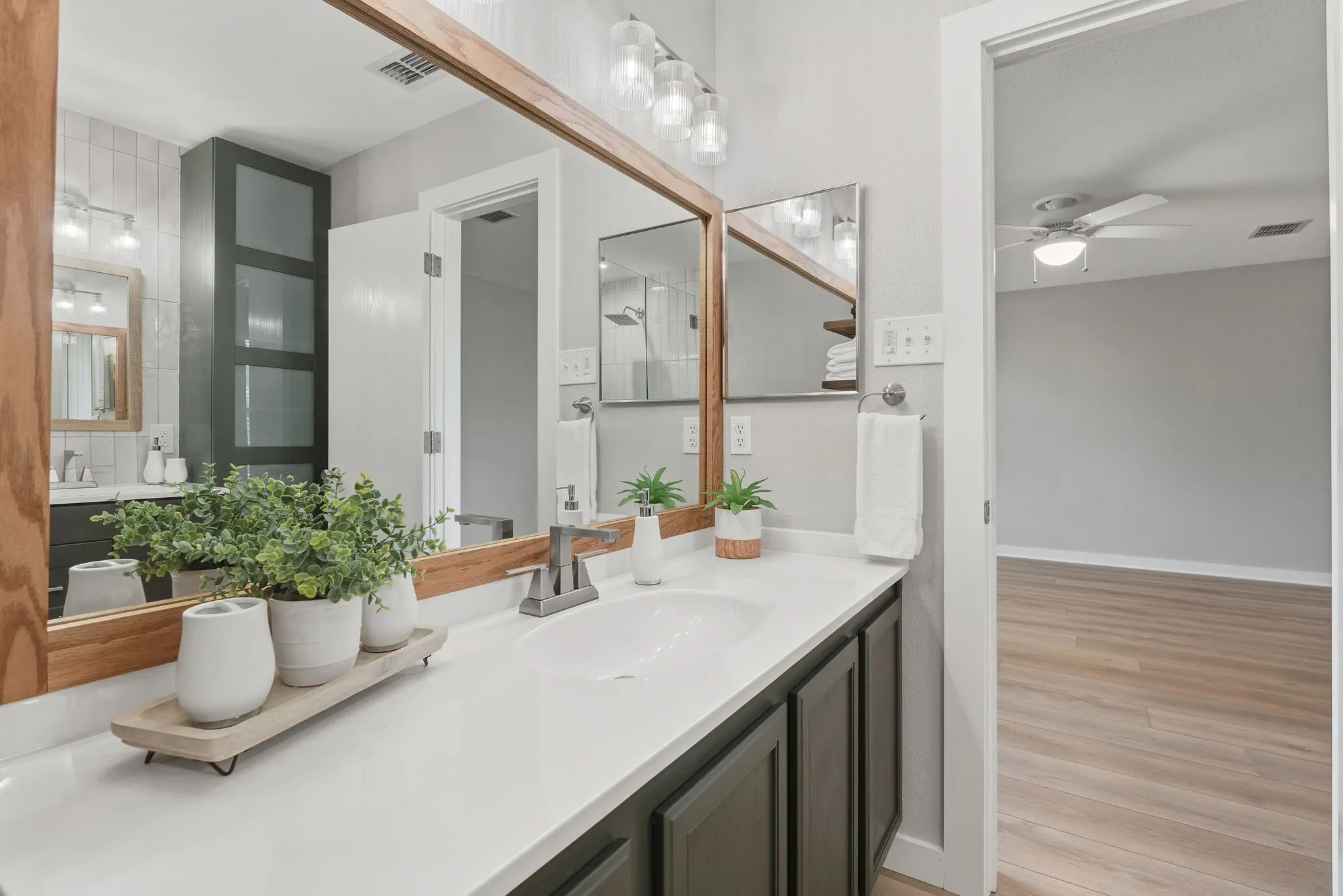 Updated vanity area features a long countertop, modern fixtures, framed mirror and a clean contemporary design.