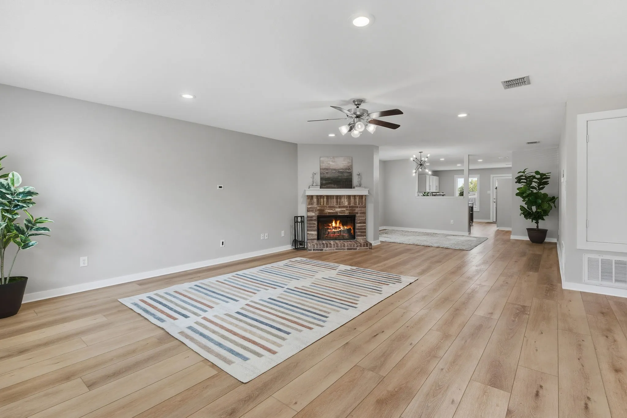 Spacious family room features updated LVP flooring, recessed lighting and a classic brick wood-burning fireplace.