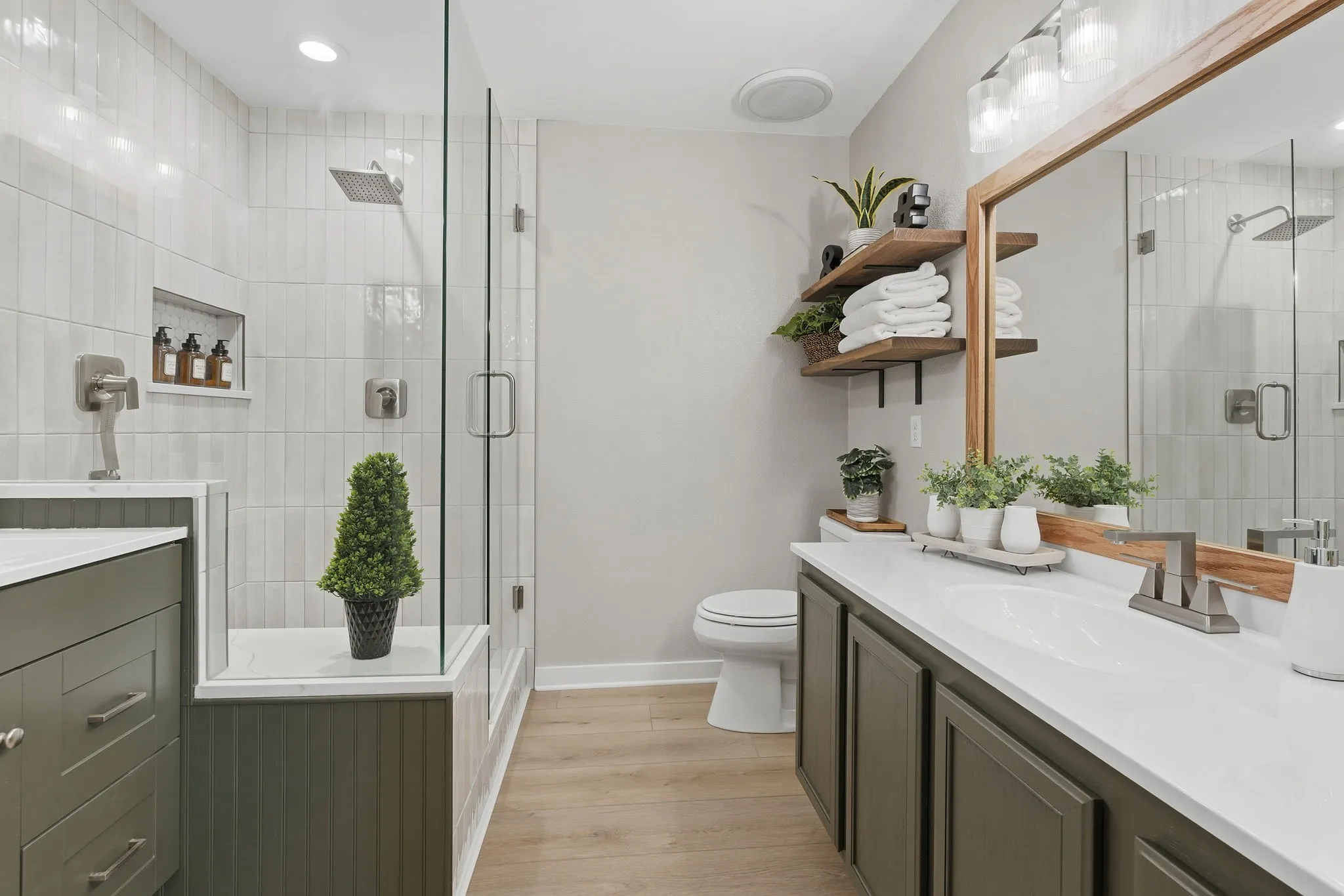 Beautifully updated primary bath features a spacious glass-enclosed shower, modern vanity, open shelving and stylish finishes.