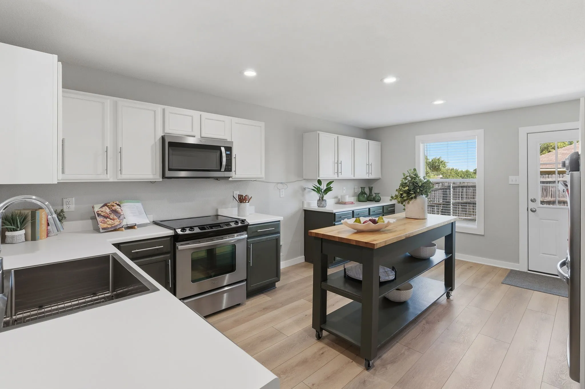 Bright updated kitchen features painted cabinetry, stainless appliances, recessed lighting and a large movable island.