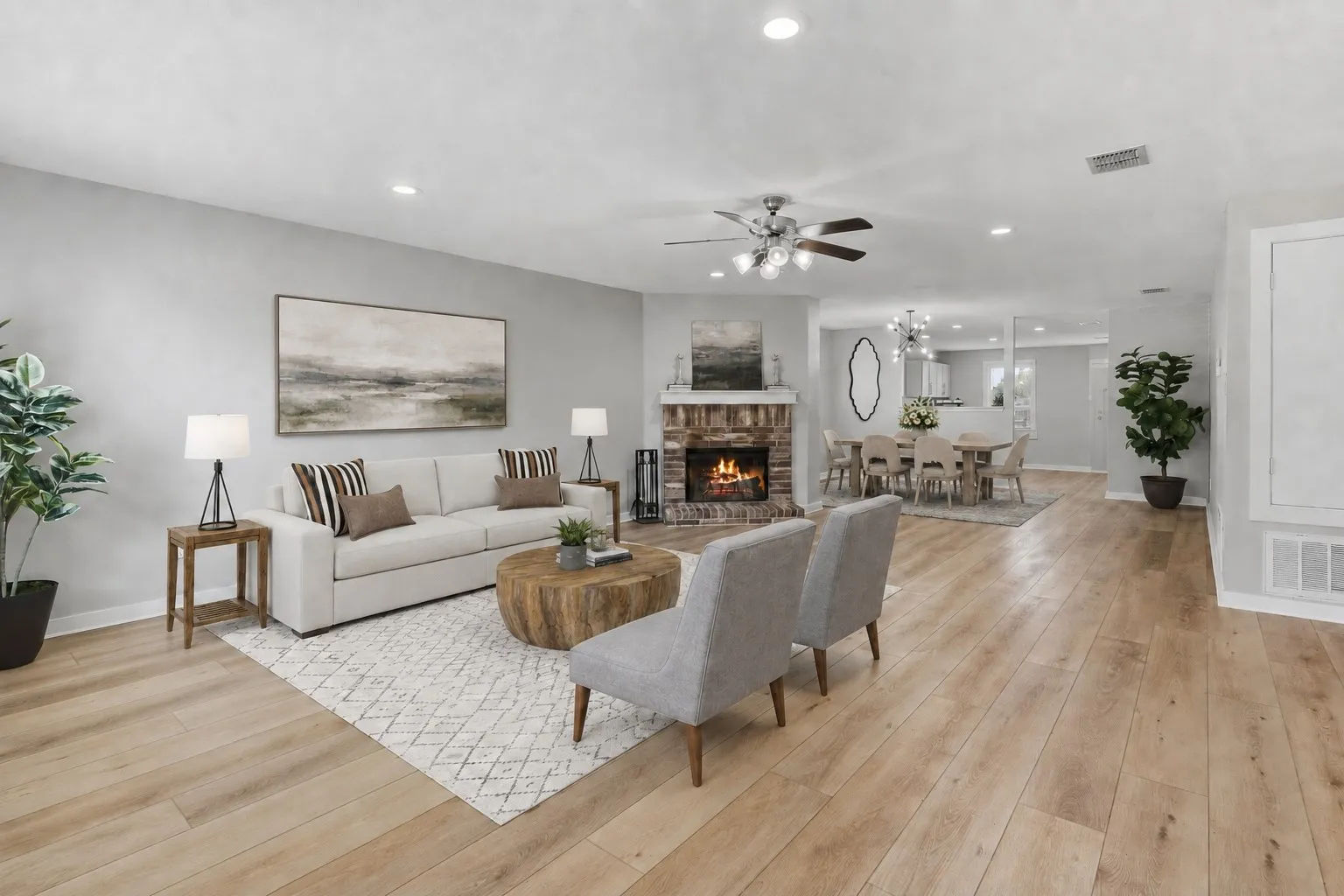 Reality Staged image showcases the spacious open-concept living area with LVP flooring, recessed lighting and a brick wood-burning fireplace.
