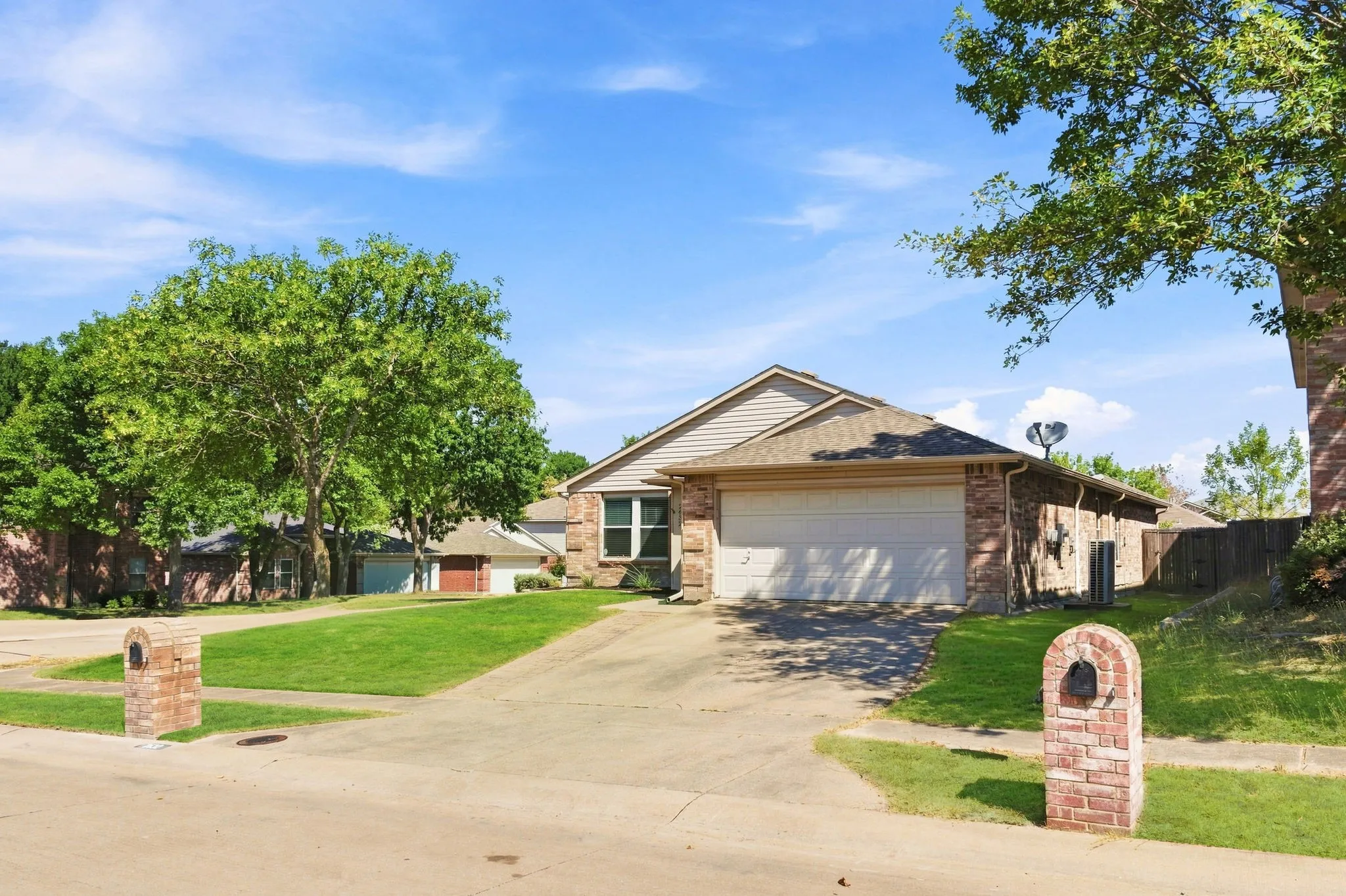 Welcoming front exterior highlights the home’s brick accents, two-car garage, mature tree and attractive corner-lot setting.