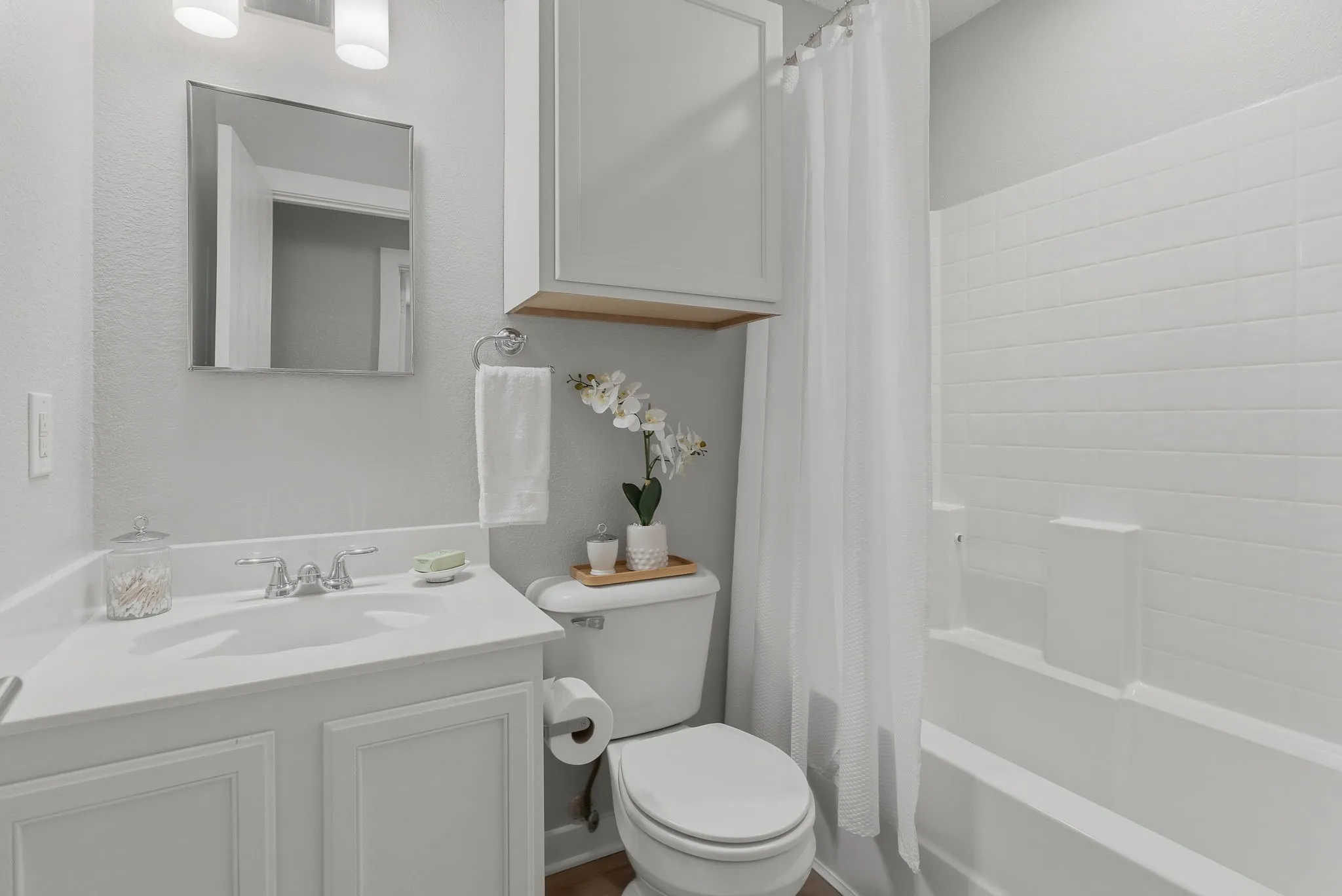 Full secondary bath features a tub-shower combination with crisp white tile, vanity storage and a clean neutral palette.