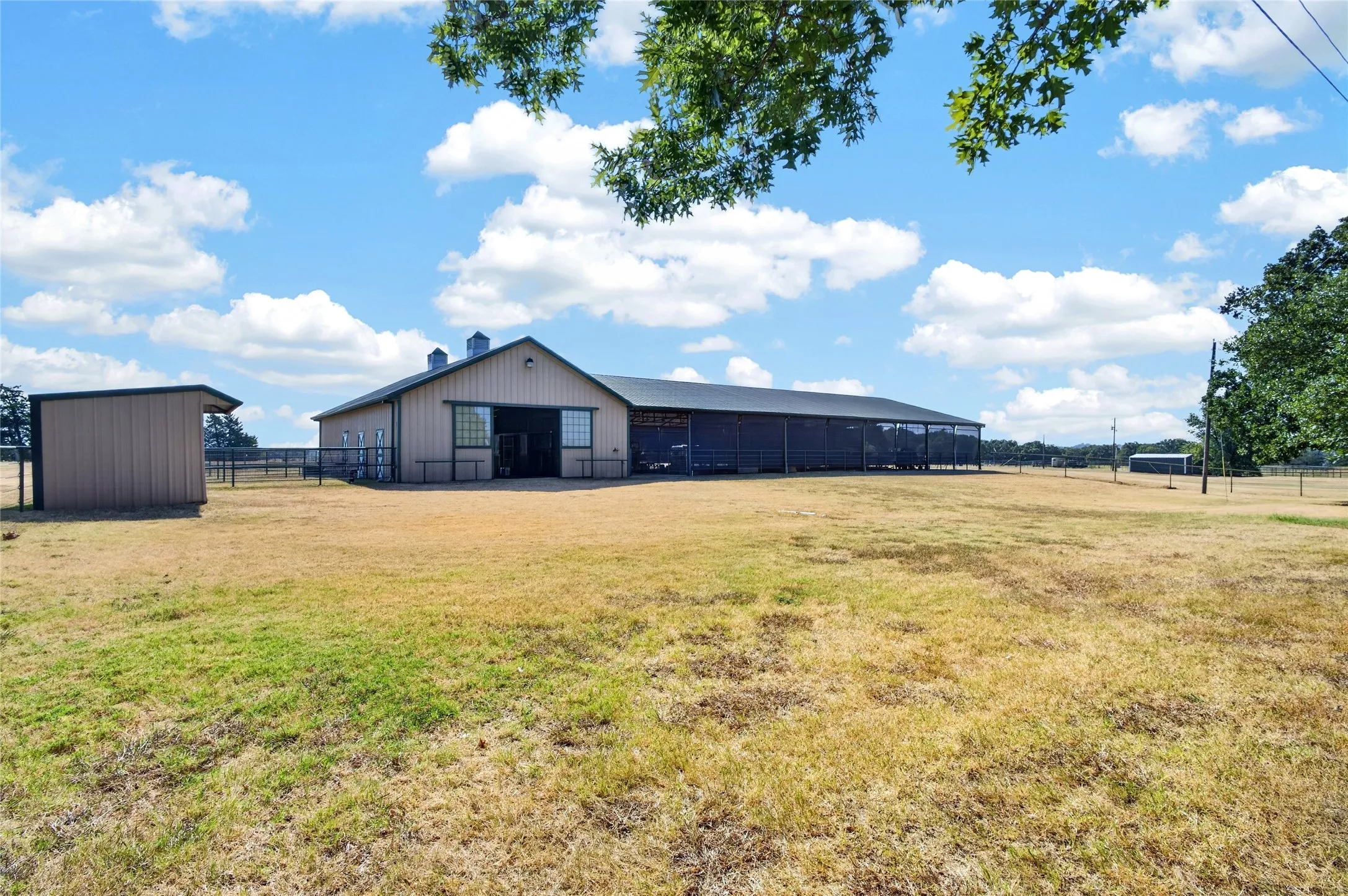 6 stall barn with conditioned rooms and training ring, loafing shed to the left and another barn to the right