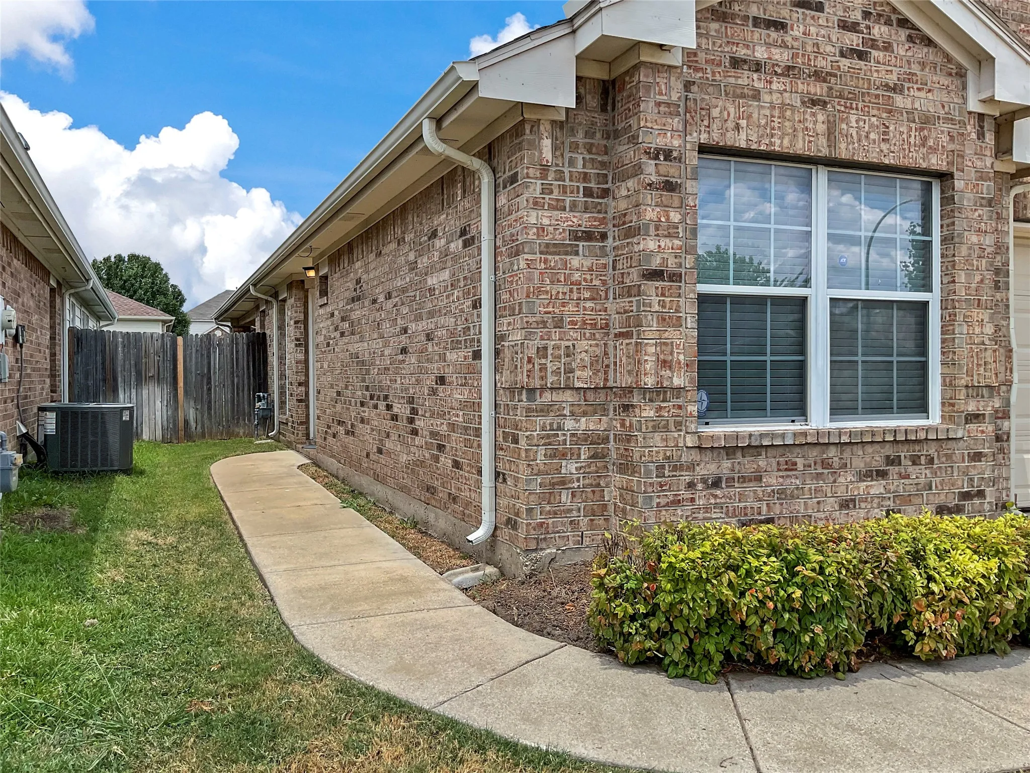 View of side of property with central AC unit and a yard