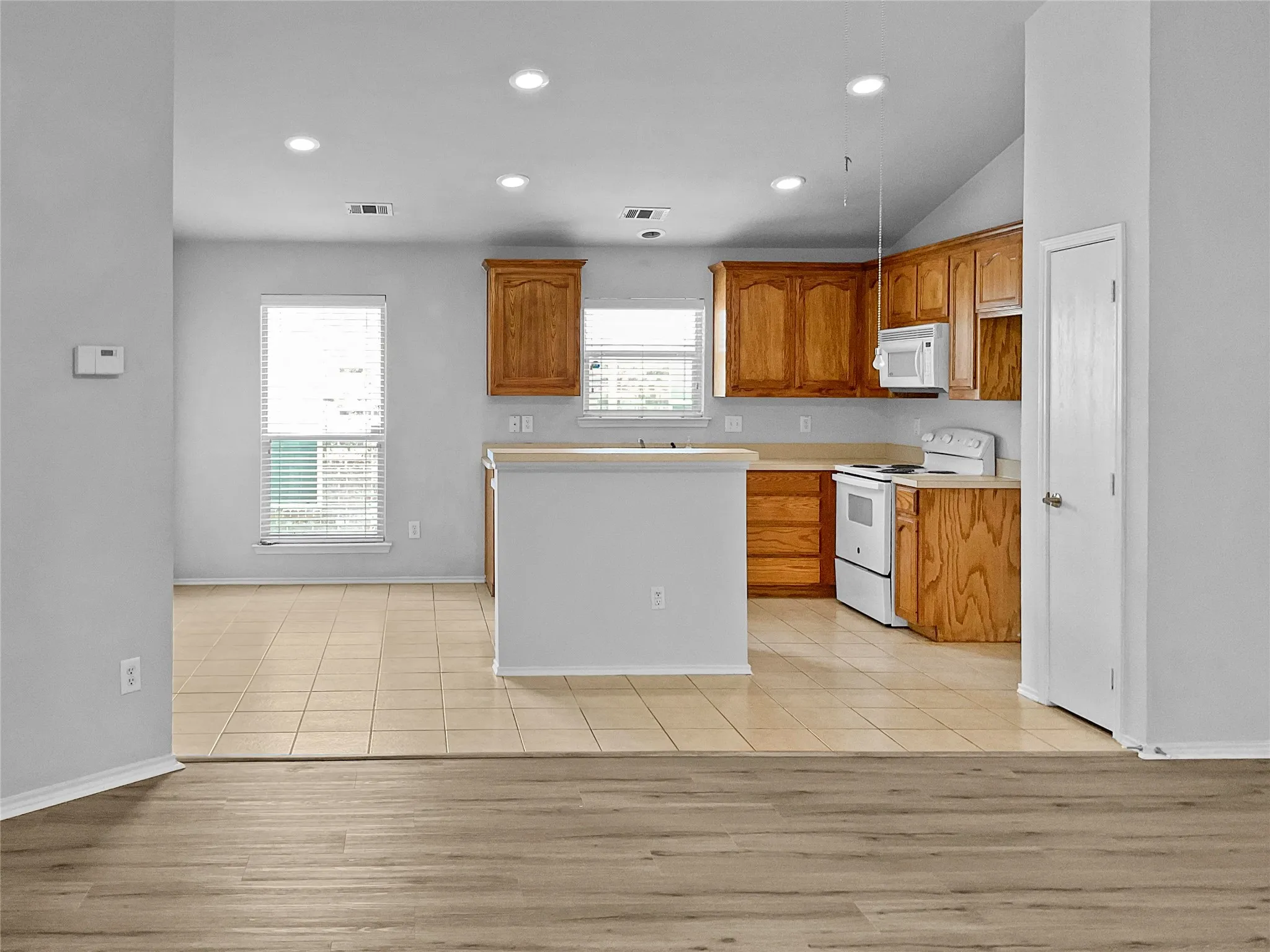 Kitchen featuring white appliances, vaulted ceiling, and light hardwood / wood-style flooring