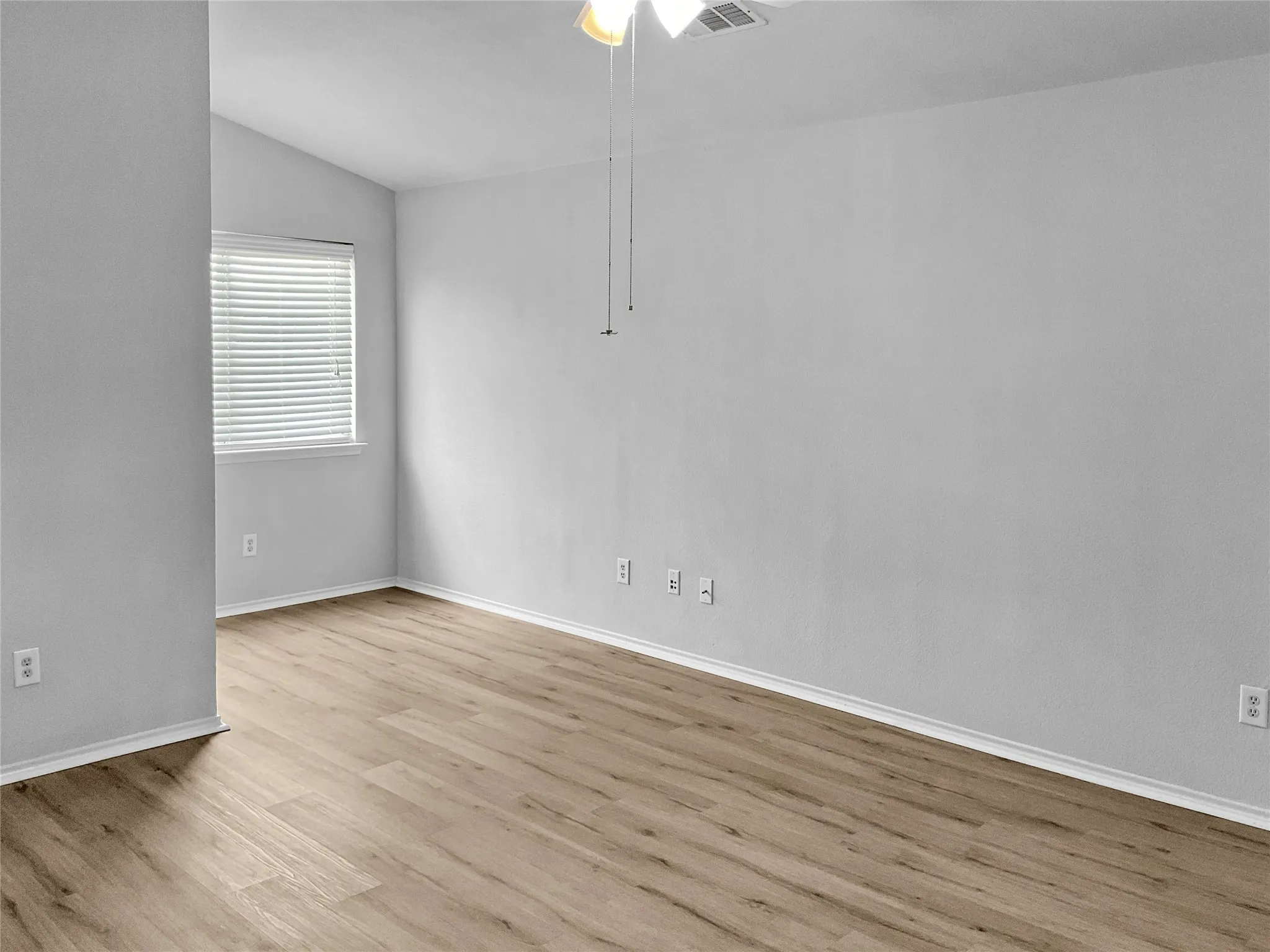 Empty room with light hardwood / wood-style floors, ceiling fan, and vaulted ceiling