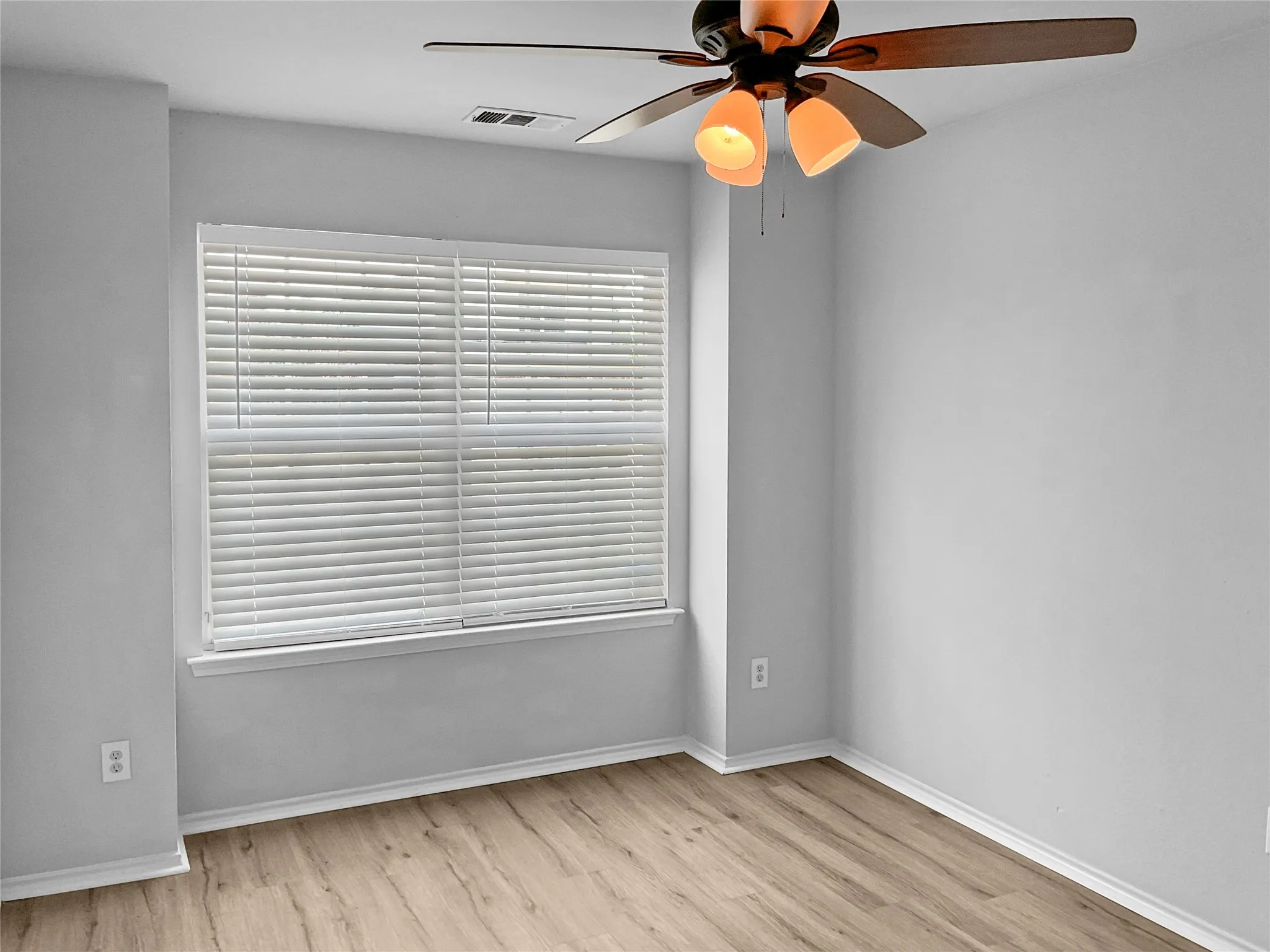 Empty room with ceiling fan and light hardwood / wood-style floors