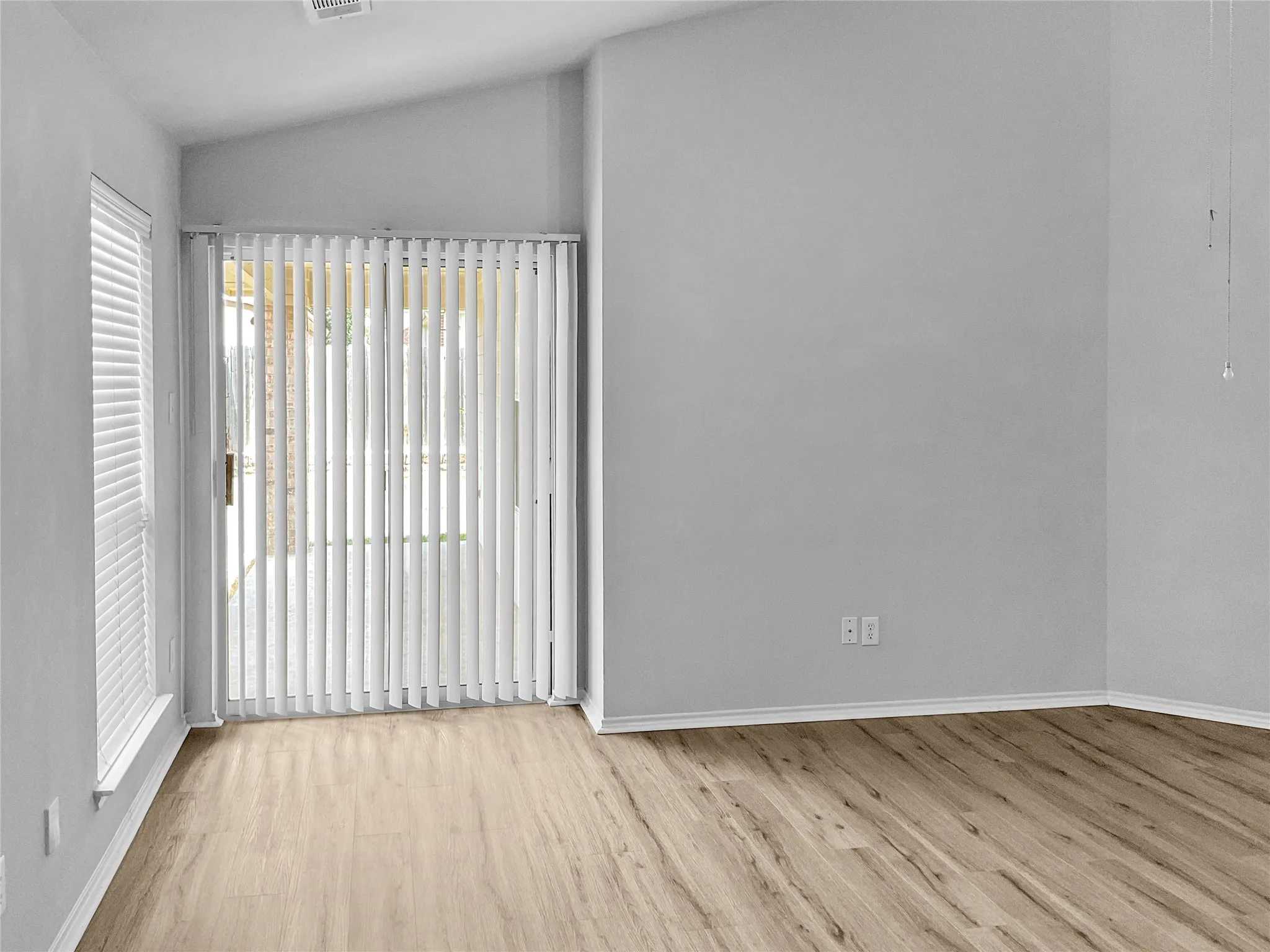 Empty room with a healthy amount of sunlight, light hardwood / wood-style floors, and lofted ceiling