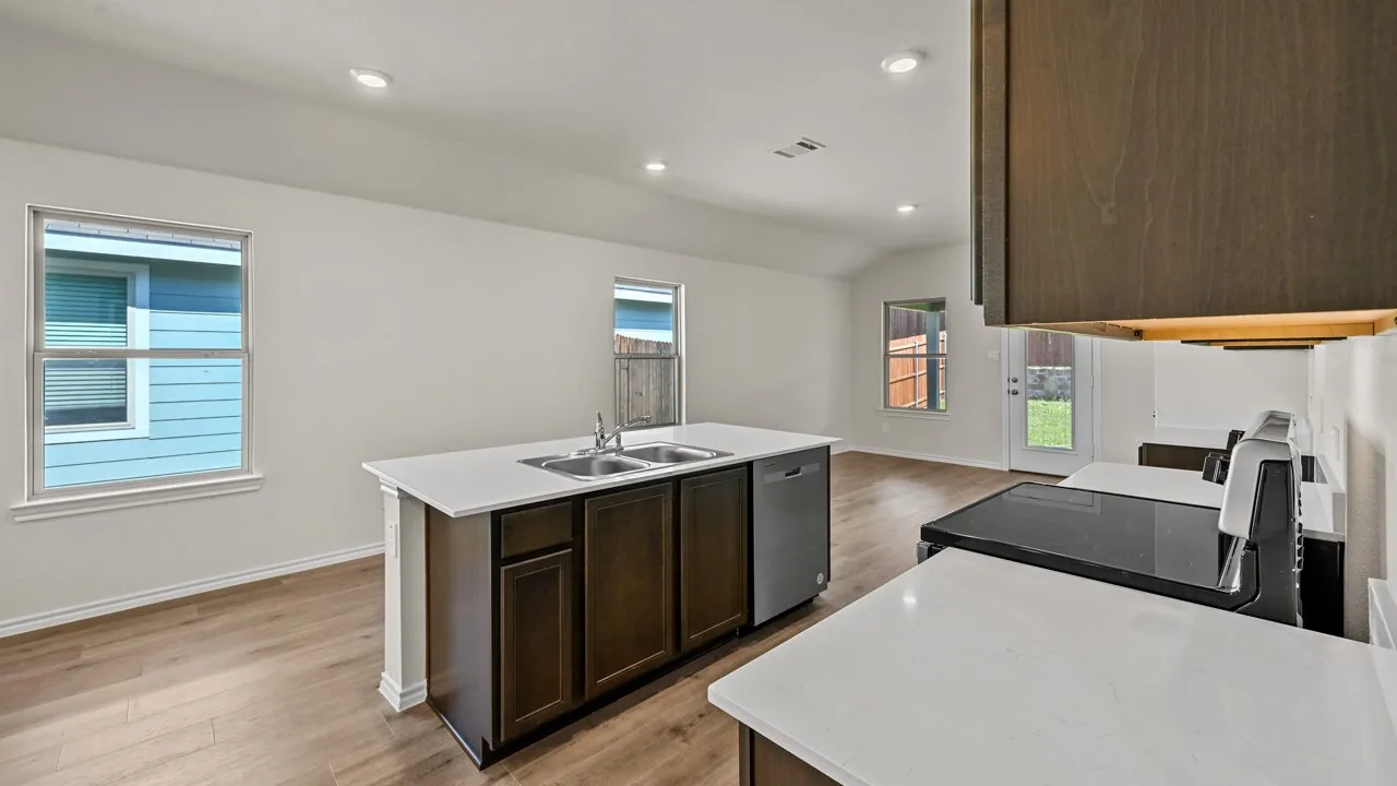 Kitchen island with double basin sink, white countertops, wood-finish flooring, and recessed lighting