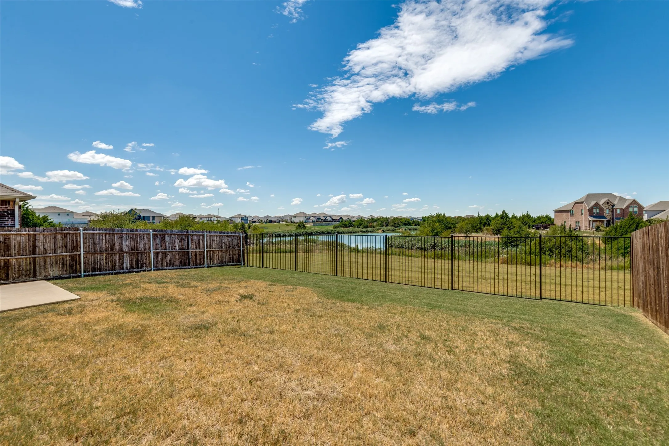 Peaceful lake views from the backyard, with privacy fencing along the sides and wrought-iron fencing across the back to keep the view open.