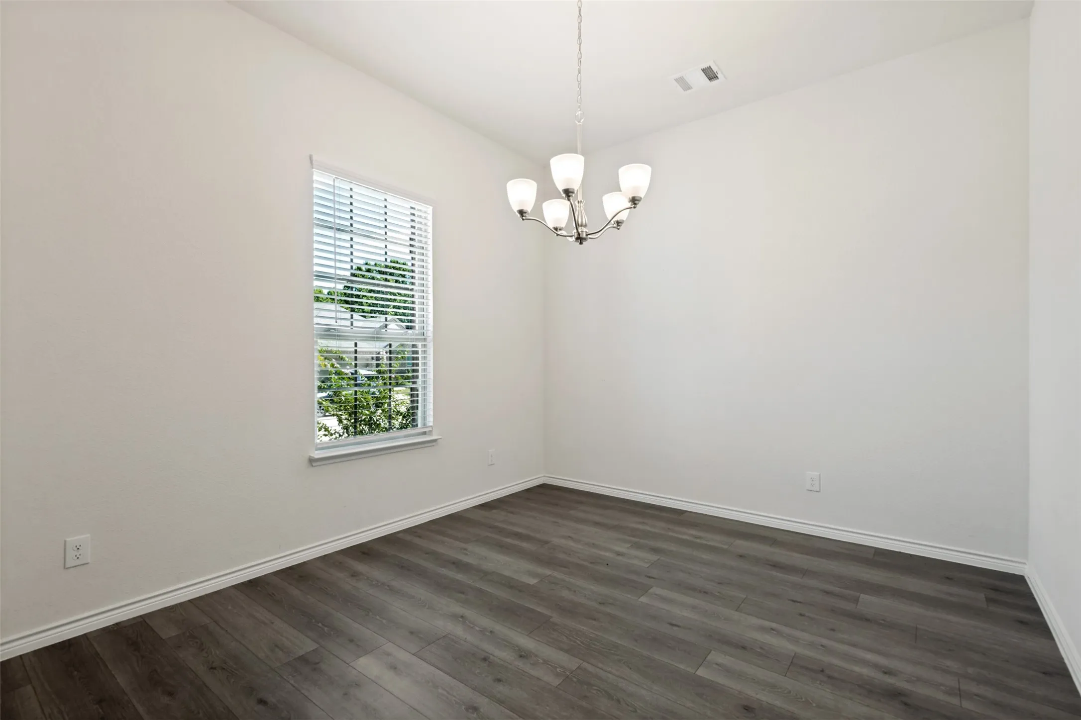 Bright dining room with LVP flooring, a large window for natural light and plenty of space for everyday meals or entertaining.