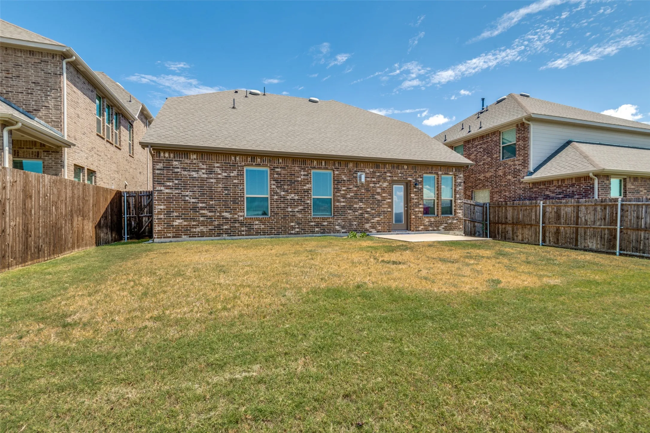 Backyard view of the home featuring an open patio with plenty of space for outdoor seating and entertaining.