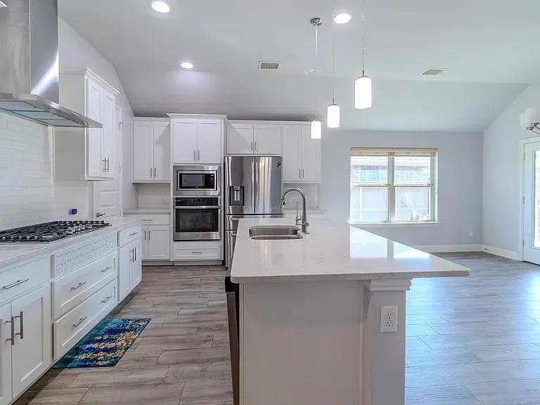 Kitchen featuring white cabinetry, stainless steel appliances, a large center island with a sink, wood-finish flooring, and recessed lighting