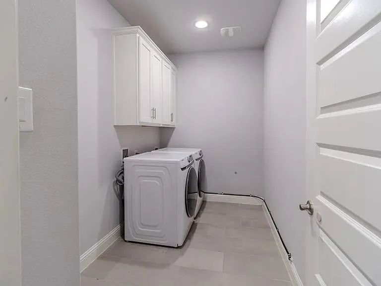 Laundry area featuring white cabinetry, a single overhead light, and a white paneled door