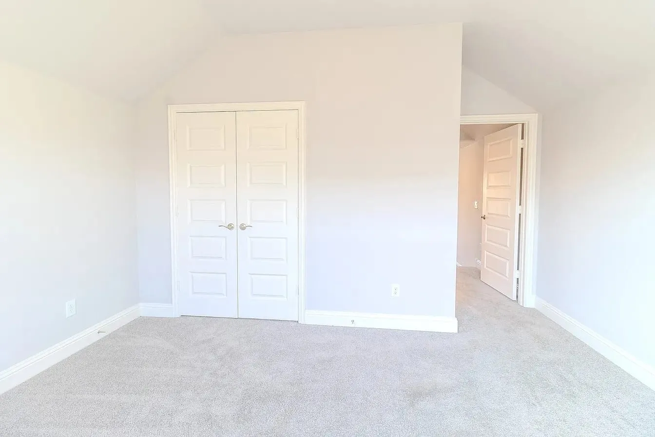 Vaulted ceiling, paneled double doors, light-toned carpeting, and crisp white trim