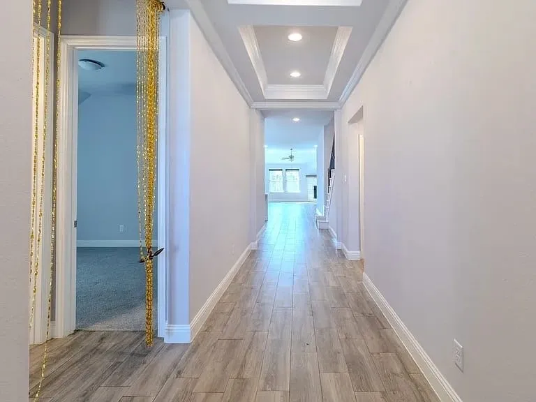 Recessed lighting, tray ceiling, wood-finish flooring, white baseboards, and white wall paint