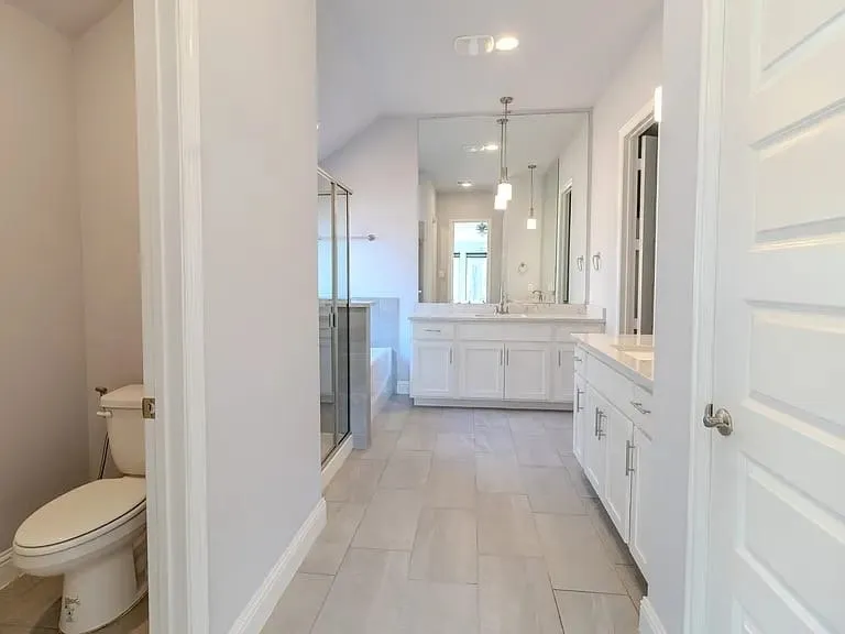 Dual vanity with white cabinetry and integrated sinks, full-length mirror, glass-enclosed shower, and a white soaking tub