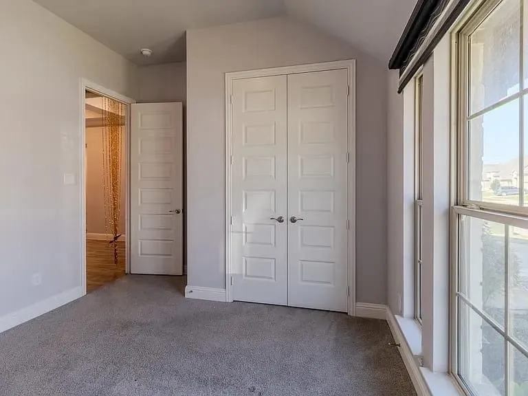 Gray carpeting, white trim, and a window with white sills and grilles
