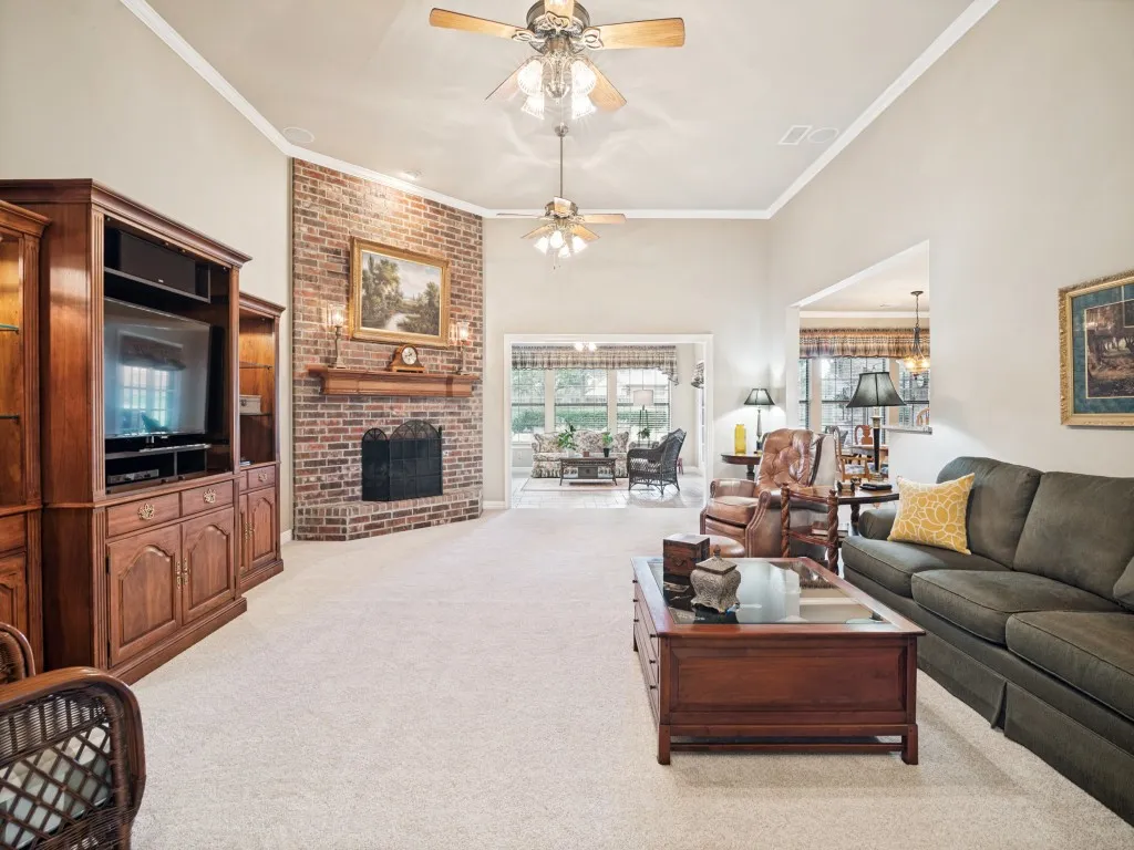 Oversized living room features a floor to ceiling fireplace with open views to the sunroom and kitchen.