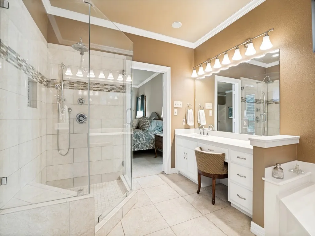 The ensuite primary bathroom features tiled shower with glass surround and separate vanities.