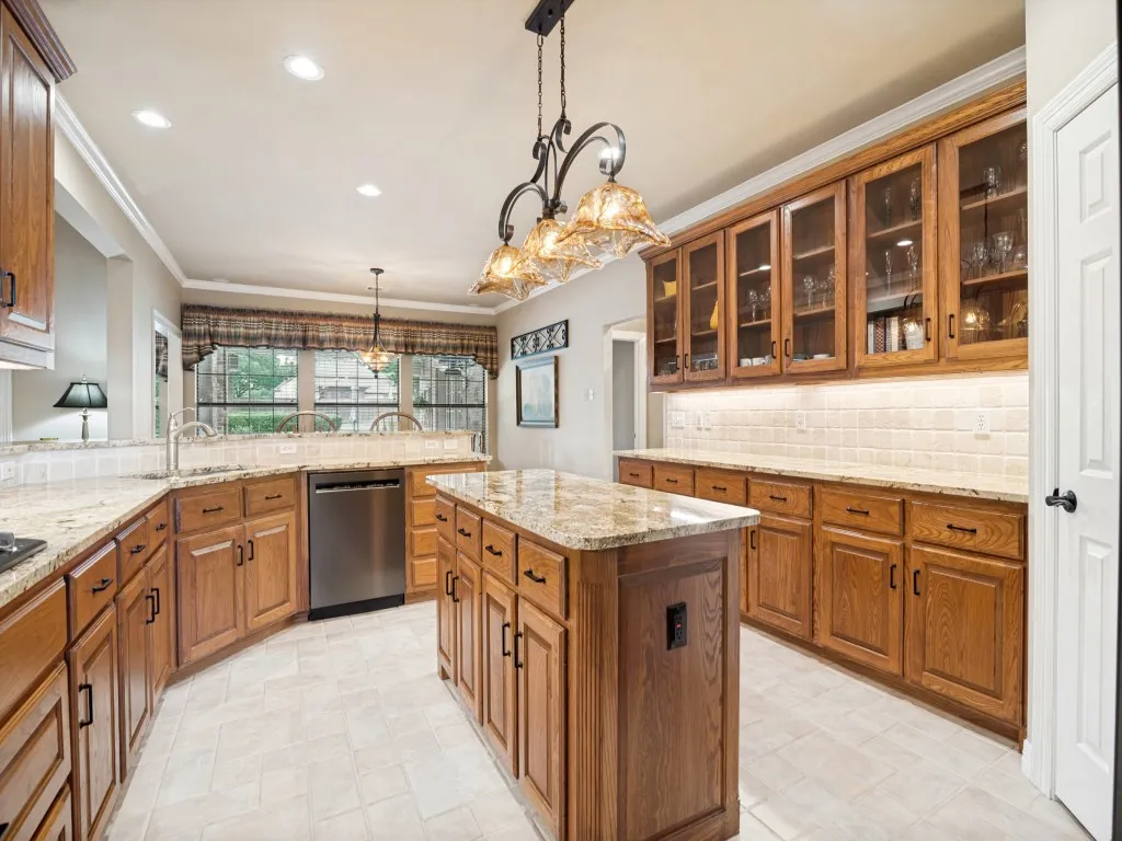 Spacious kitchen boasts granite countertops, decorator lighting and massive amounts of storage.
