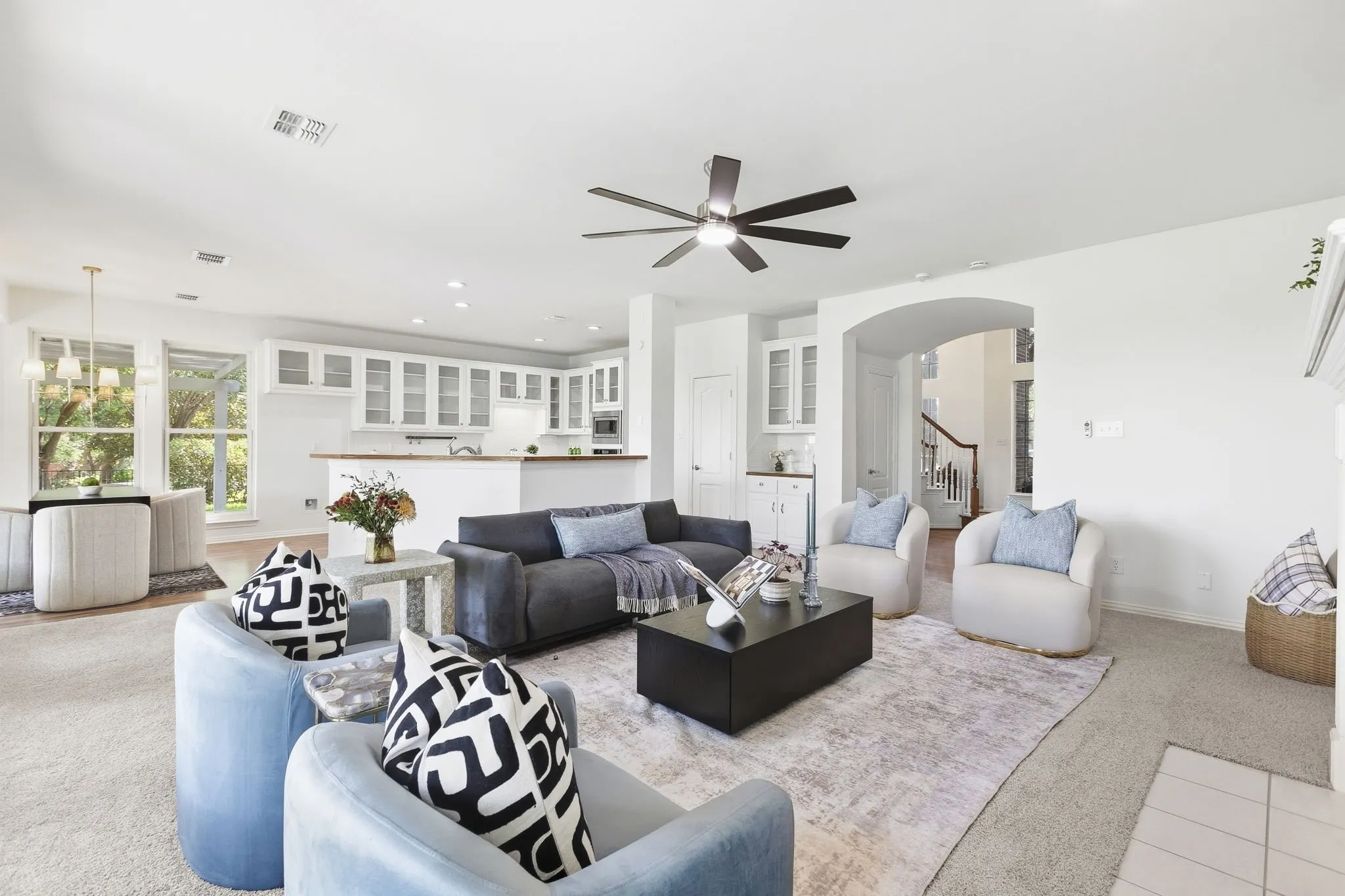 Open-concept living area featuring a ceiling fan, recessed lighting, and a kitchen with white cabinetry
