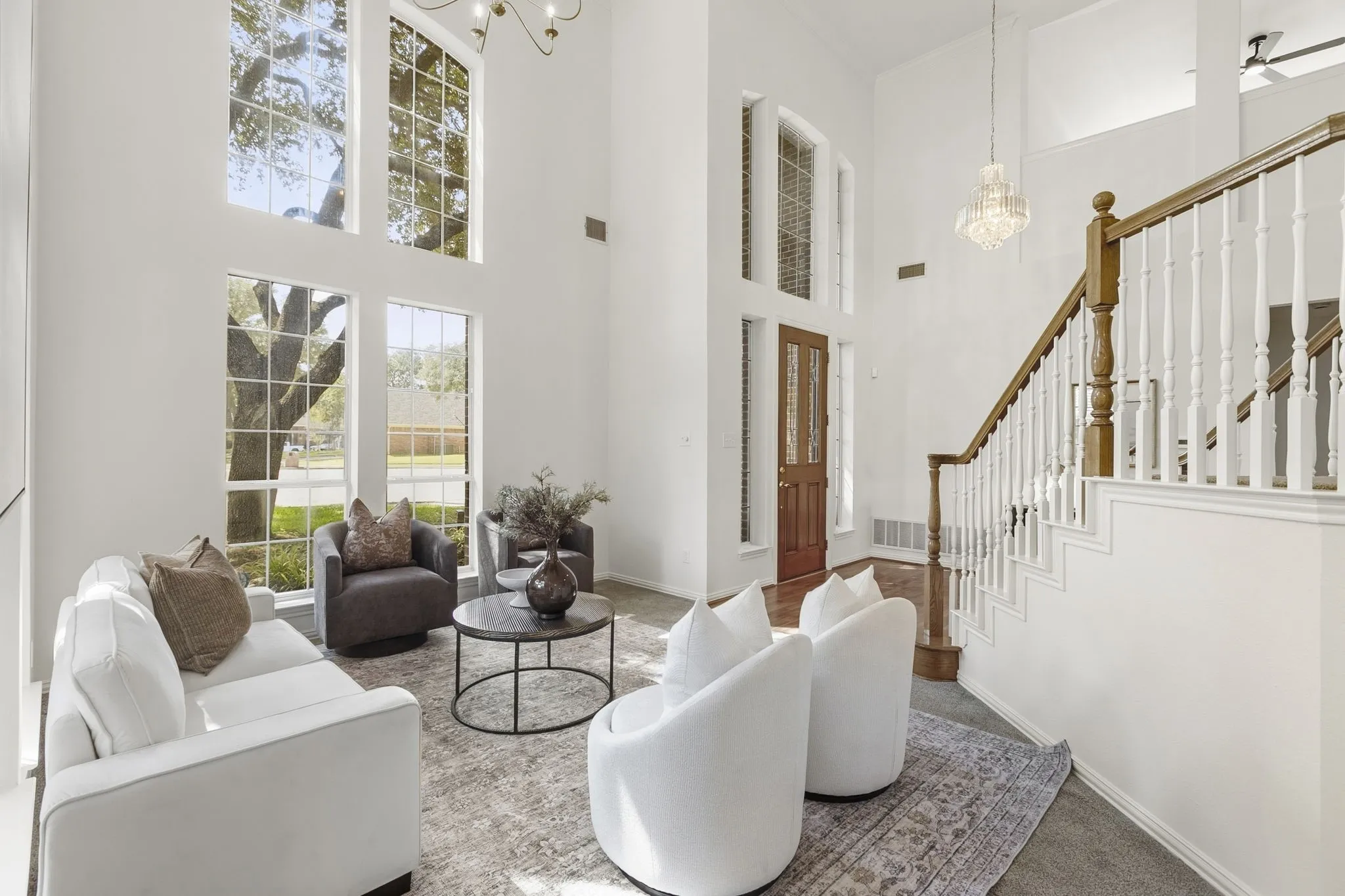 Formal Living Rm: Two-story entryway featuring wood flooring, a grand staircase with wood banister, and a chandelier