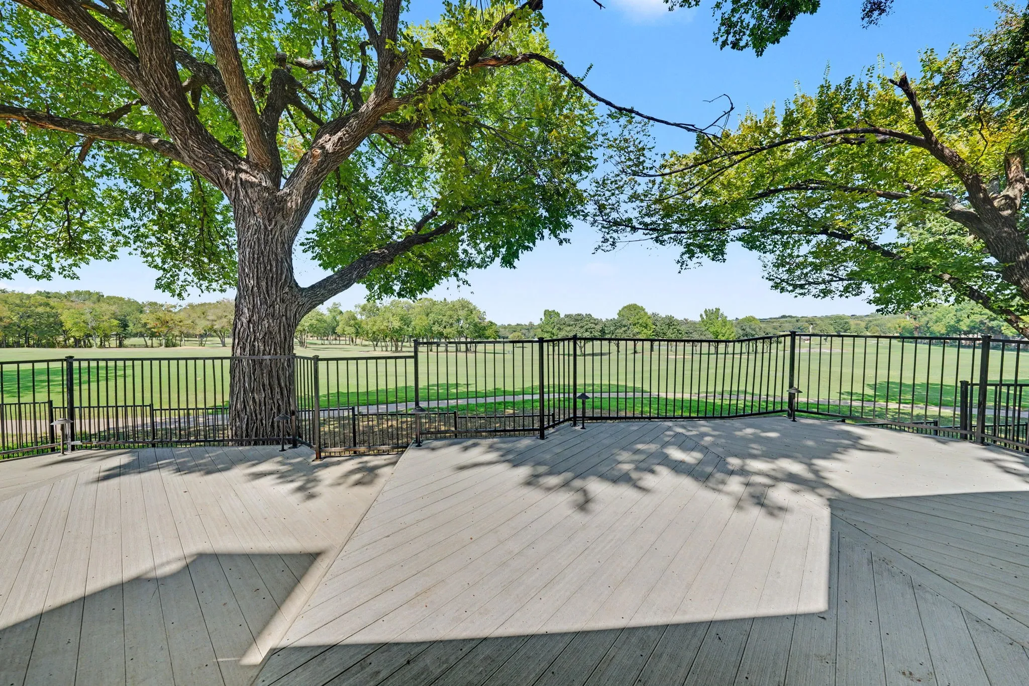 Expansive views of the Firewheel Golf Course, near 3rd hole of the Old Course from interior windows and oversized exterior deck featuring composite decking, black metal fencing, and mature trees.