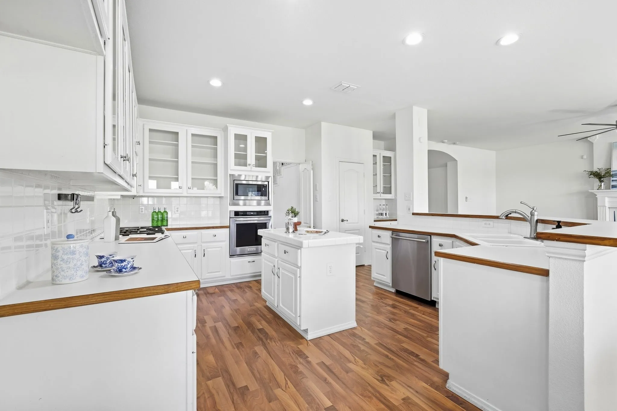 Kitchen with white cabinetry, wood type finish flooring, new recessed lighting, and stainless steel appliances, white gas cook top