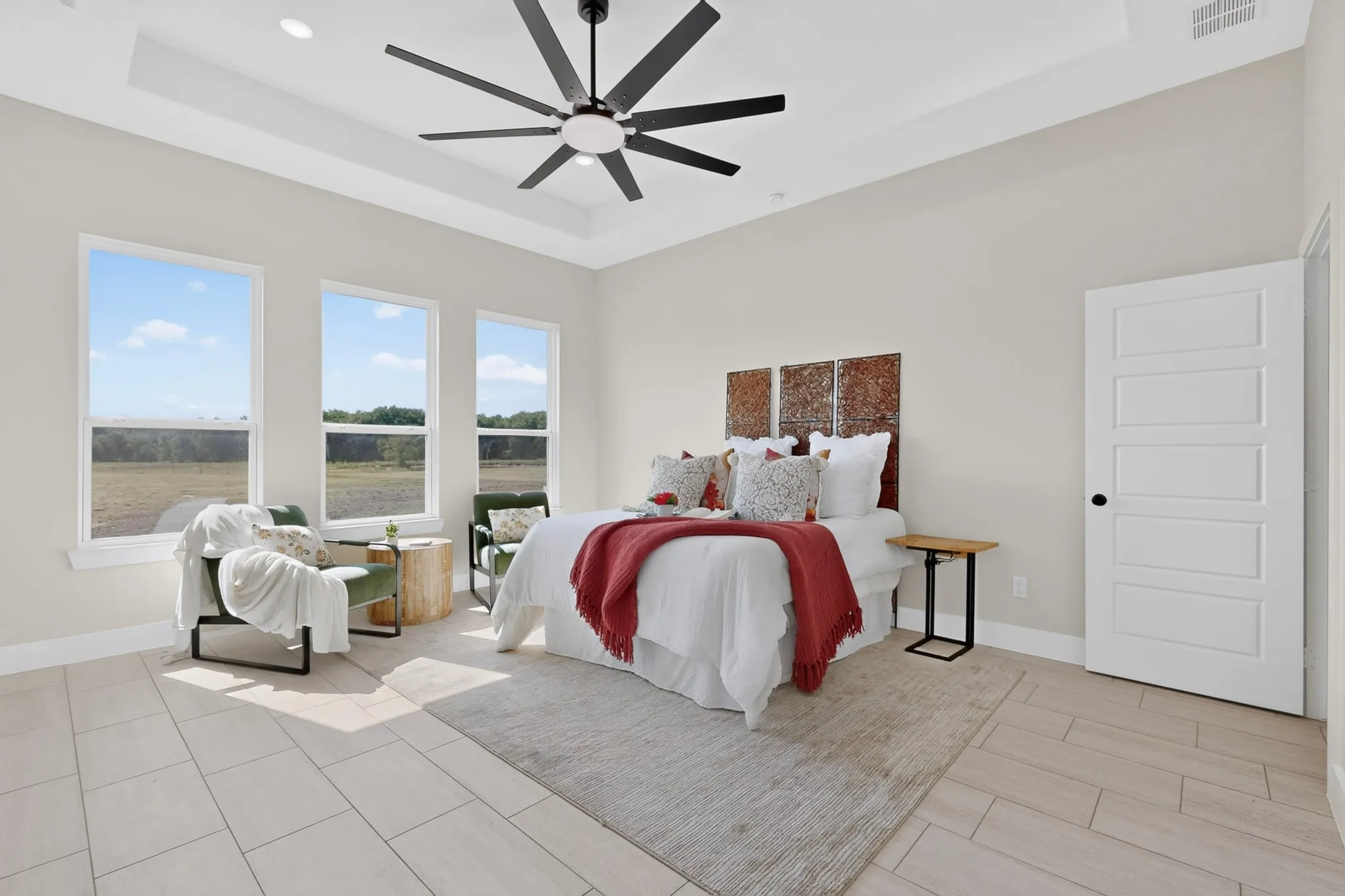 Tray ceiling with recessed lighting and a ceiling fan, three large windows, light-toned tile flooring, and a five-panel interior door with matte black hardware