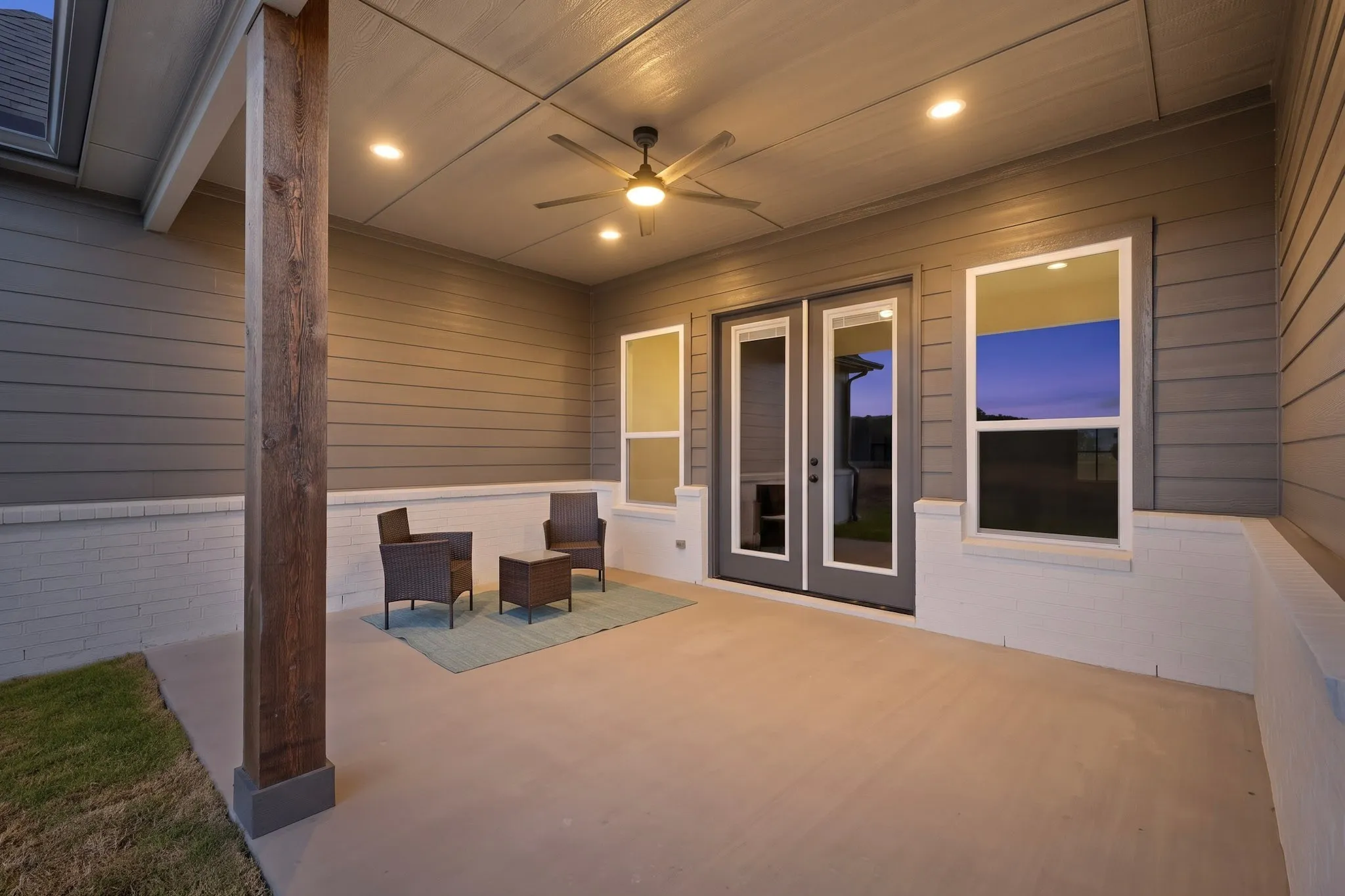Covered patio with polished concrete flooring, recessed and ceiling fan lighting, shiplap and horizontal siding walls, and multi-panel glass doors opening to outdoor space