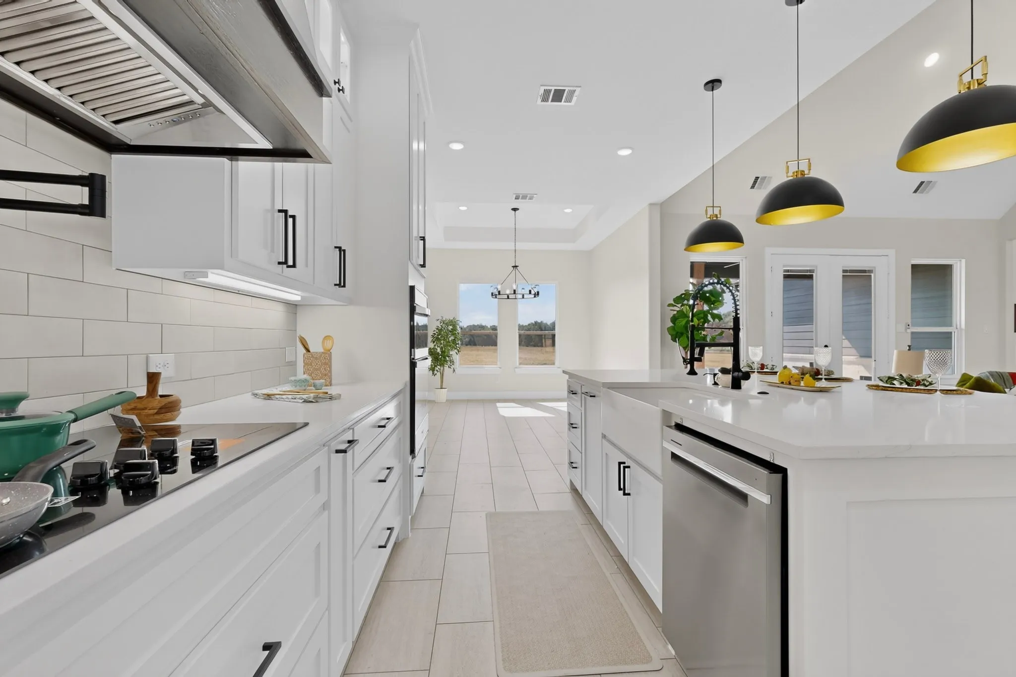 Gourmet kitchen with white cabinetry, stainless steel appliances, a large island with sink, subway tile backsplash, and decorative pendant lighting