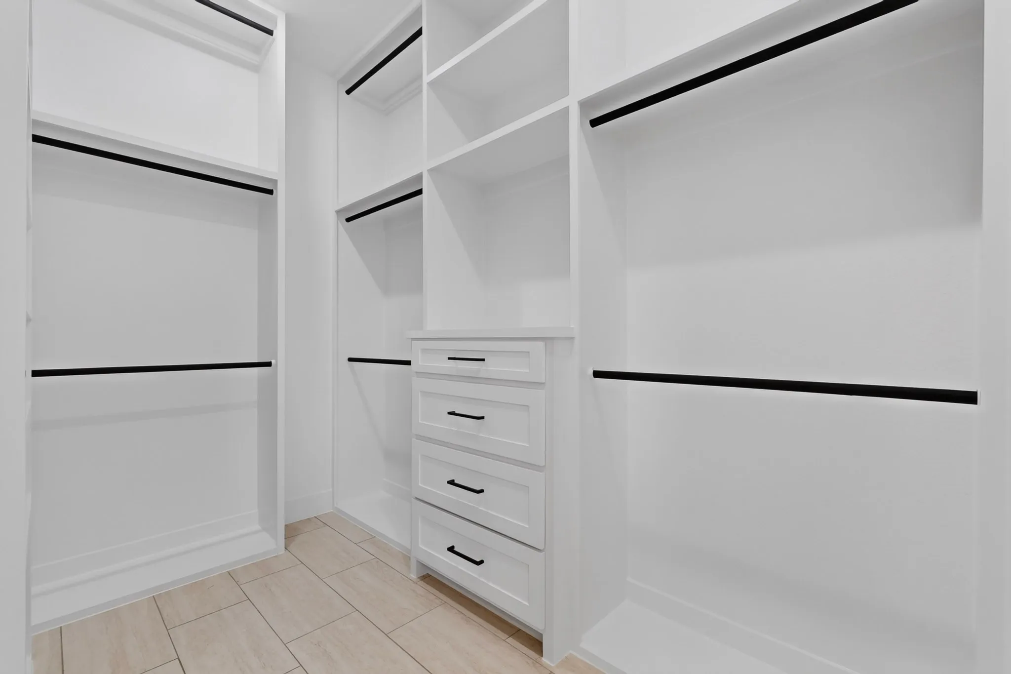 Built-in white cabinetry with drawers, open shelving, and black hanging rods