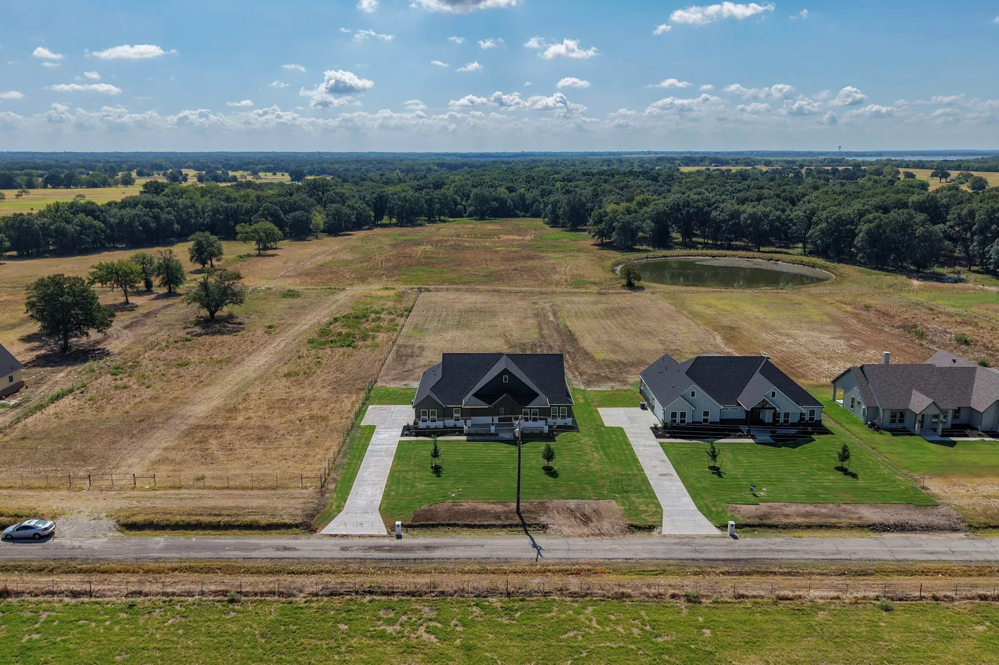 Expansive residential development featuring three newly constructed homes with modern architectural design, situated on substantial individual lots