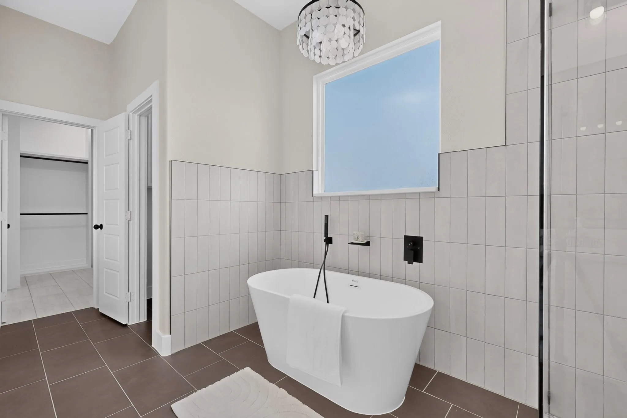 Freestanding soaking tub with matte black fixtures, tile surround, and a clear glass shower enclosure