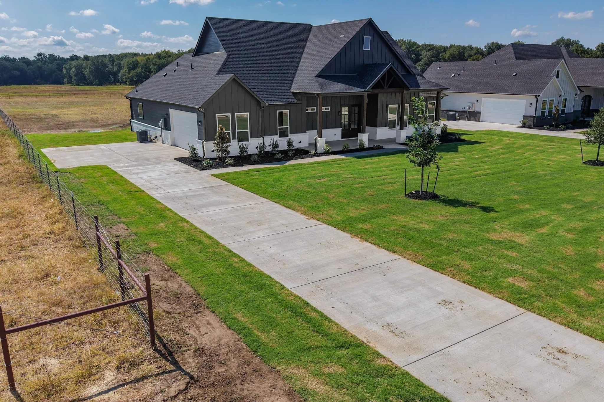 Modern farmhouse style residence with a dark gray exterior, white trim, and a prominent front porch