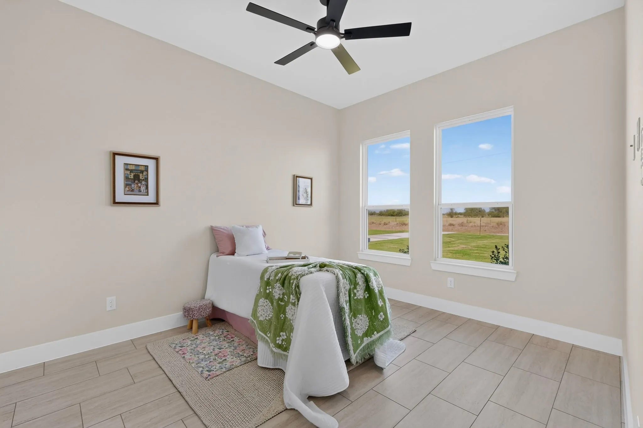 Neutral wall paint, two bright windows, wood-finish tile flooring, ceiling fan with integrated lighting