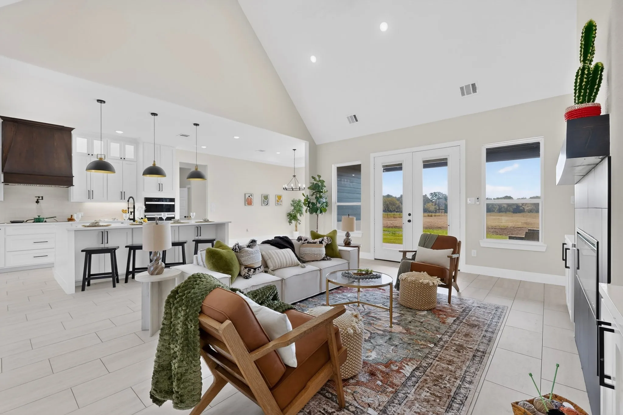 Open-concept living area featuring vaulted ceilings, wood-finish flooring, and white French doors