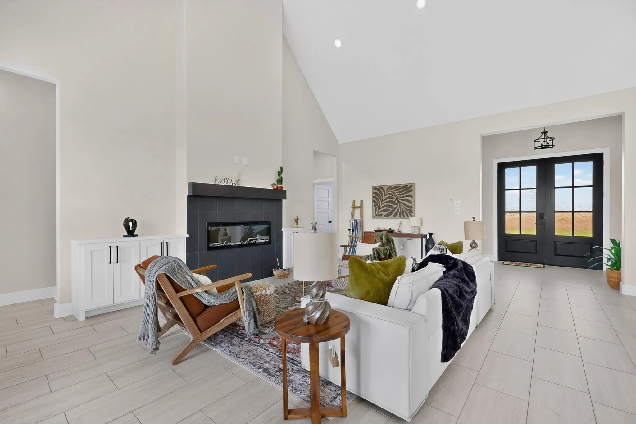Vaulted ceiling with recessed lighting, linear fireplace with a dark tile surround, light-toned tile flooring, and dark double entry doors with glass panels